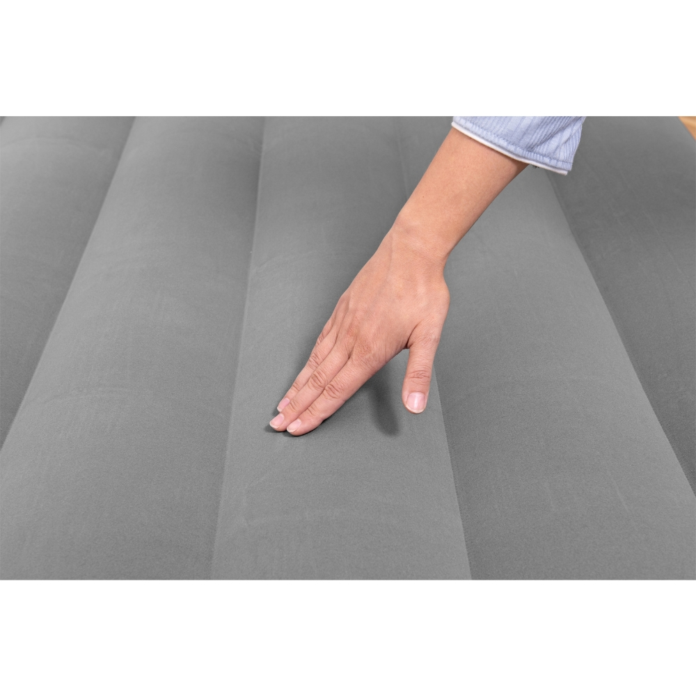 Une main touche un matelas gonflable gris. Le matelas est gris et la main est au centre.