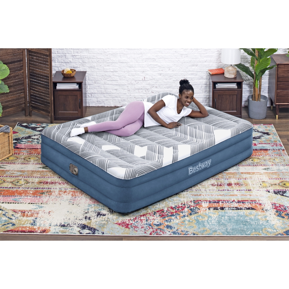 Een vrouw ligt op een opblaasbare matras met patroon. De kamer heeft een tapijt, bijzettafels en een decoratief scherm.