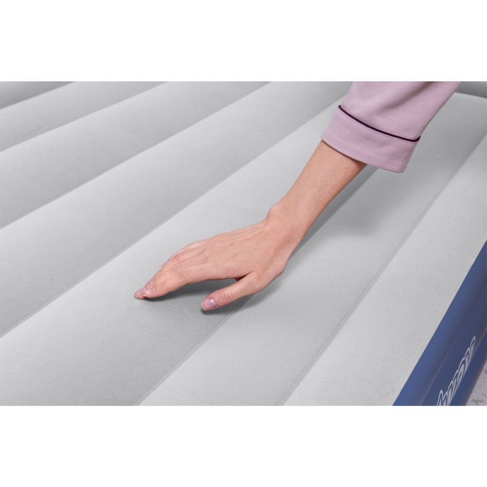 Main touchant matelas gonflable gris, gros plan, bordure bleue, fond blanc.
