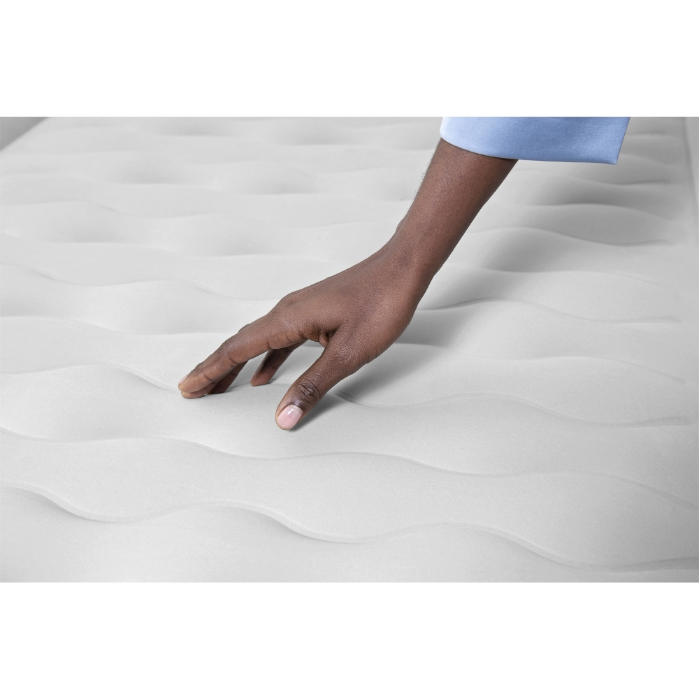 Hand raakt witte luchtmatras aan, close-up, glad oppervlak, neutrale belichting.