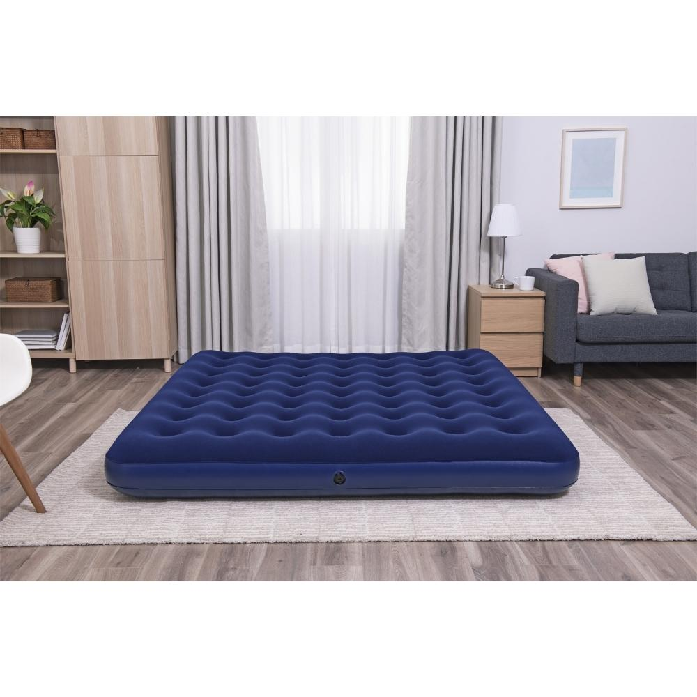 Blauwe Bestway luchtmatras op een vloerkleed in een woonkamer.