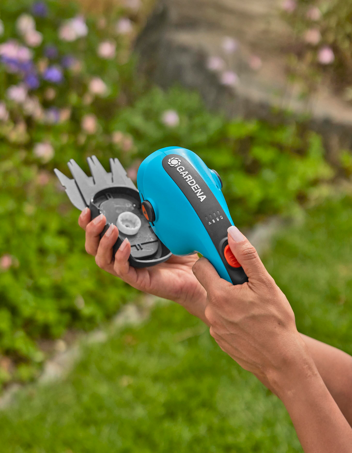 Kobieta trzymająca niebiesko-czarną elektryczną przycinarkę GARDENA.