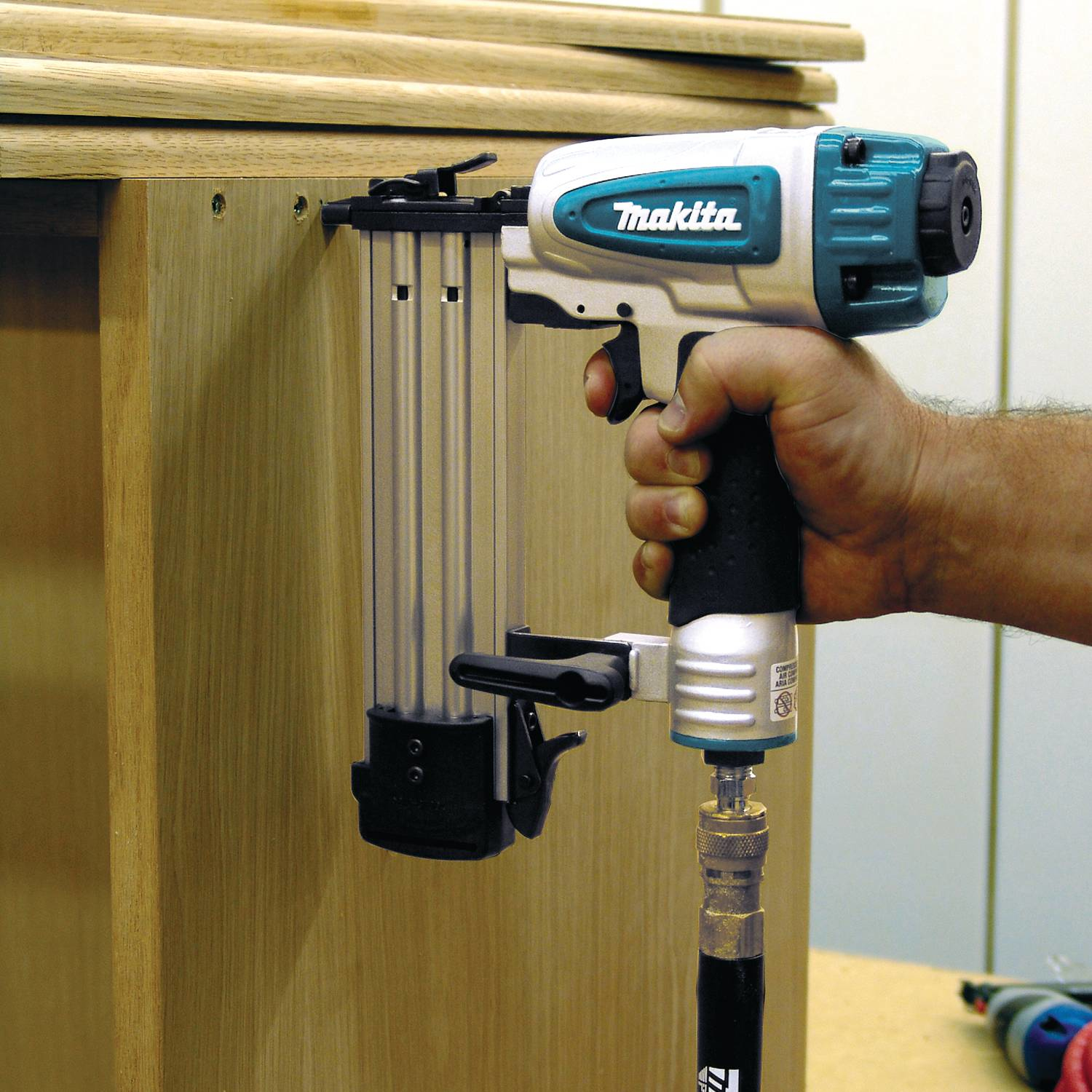 Una mano usa una sparachiodi per attaccare a un mobile di legno.