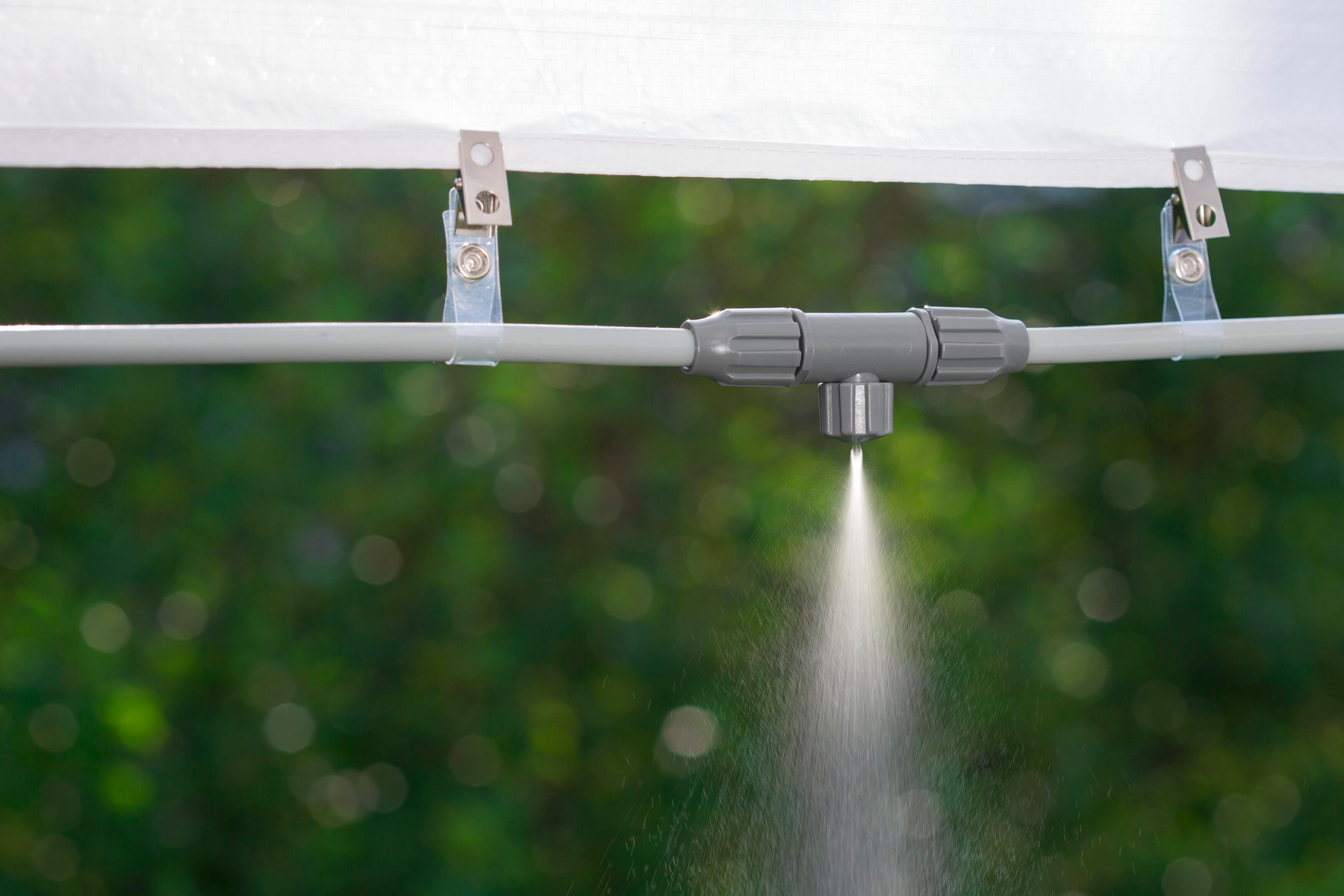 Wasser, das aus einem grauen Rohr mit einem Sprinkler spritzt.