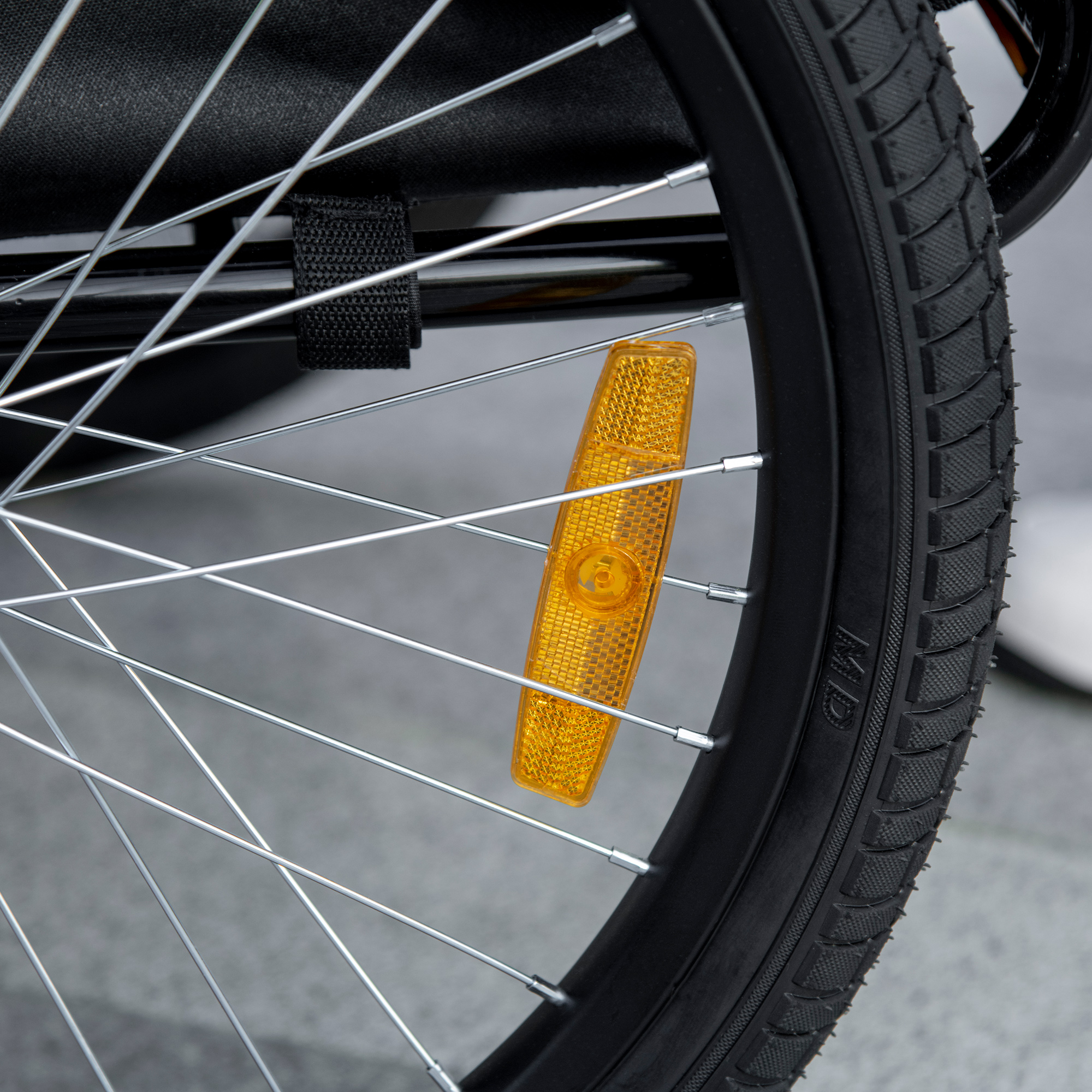 Nahaufnahme eines Fahrradrads mit einem orangefarbenen Reflektor.