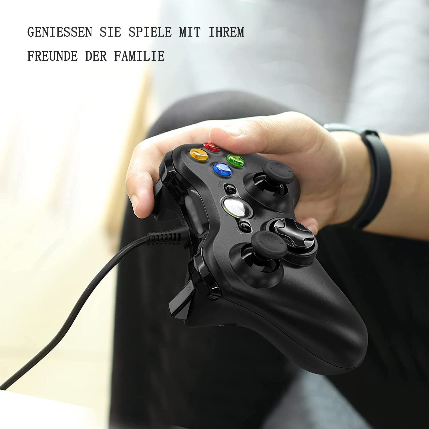 Eine Person hält einen schwarzen Gamecontroller mit bunten Knöpfen.
