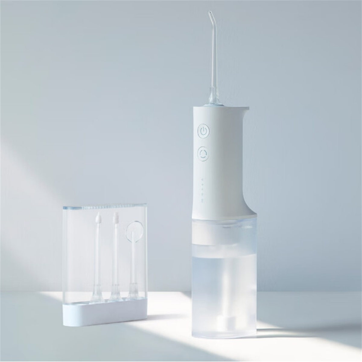 Ein weißer Wasserflosser mit einem transparenten Behälter und drei Flosserspitzen auf weißer Oberfläche.
