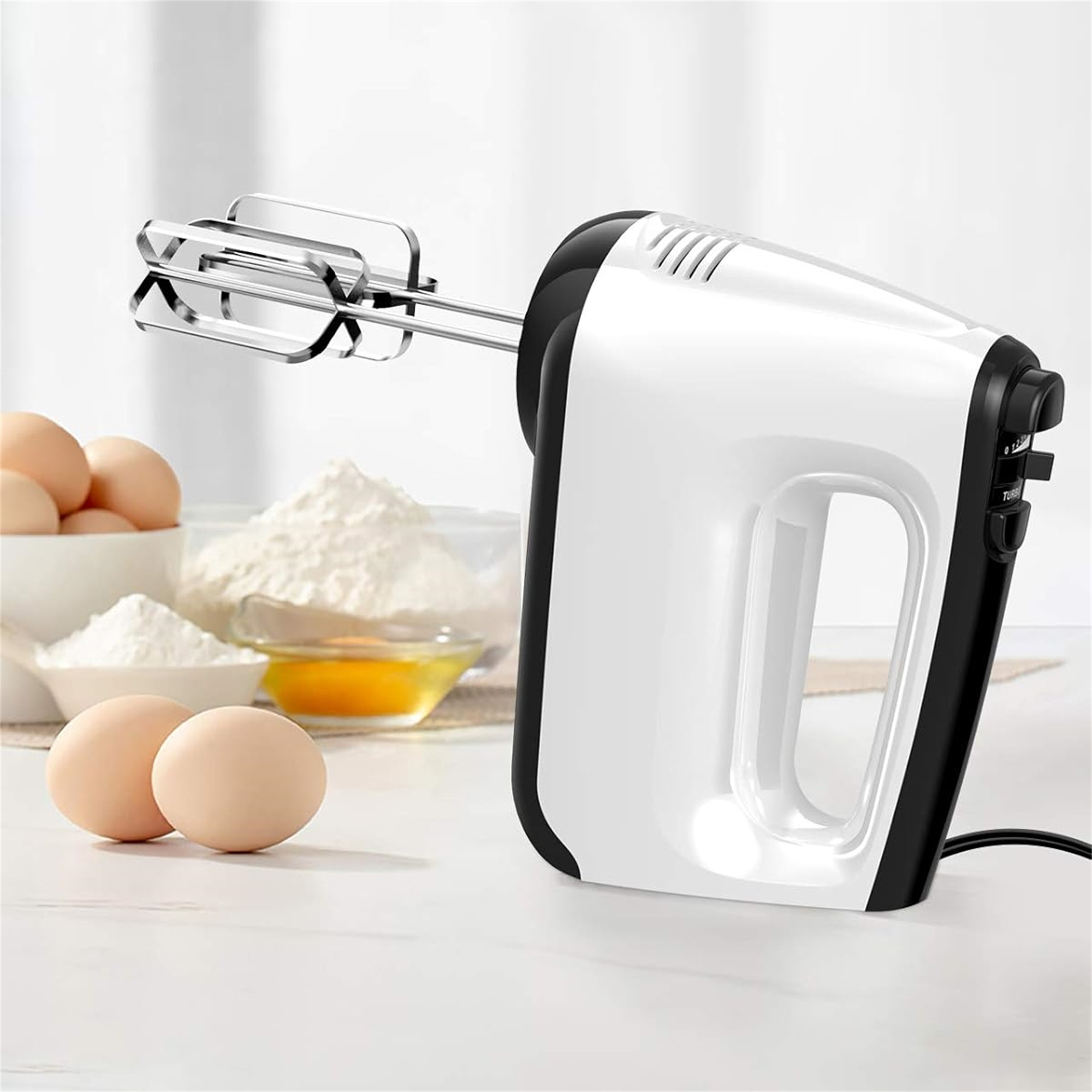 Ein weißer und schwarzer Handmixer mit Eiern und Mehl im Hintergrund.