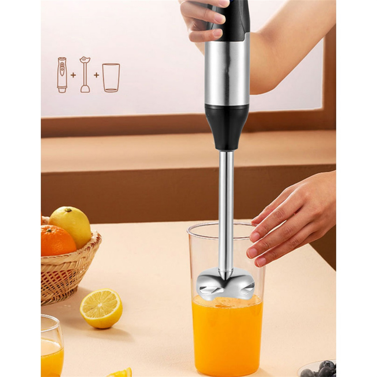 Hand vermischt Orangensaft mit einem Stabmixer in einem Glas. Orangen und Zitronen liegen auf dem Tisch.