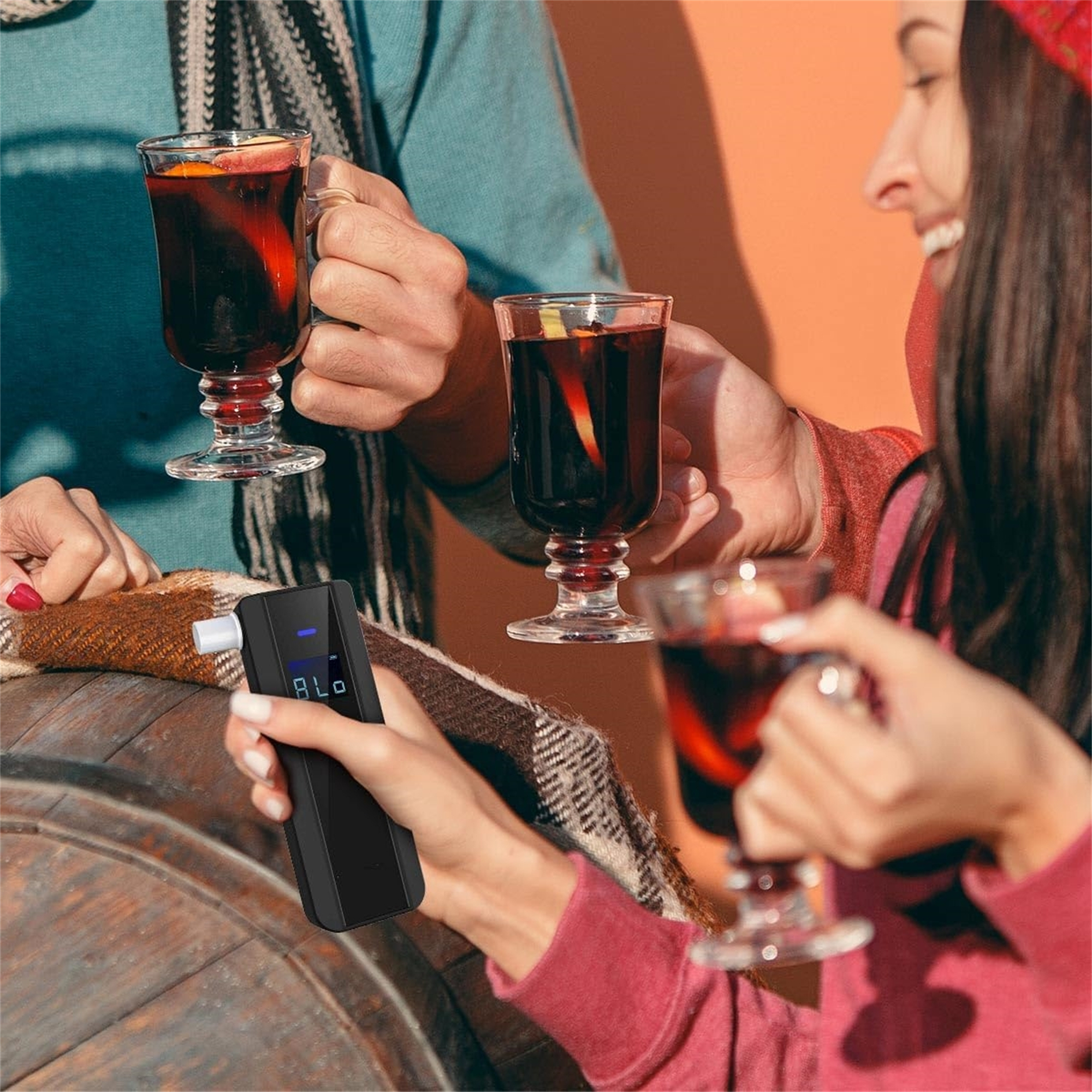 Leute halten Gläser Glühwein, eine Person benutzt einen Alkoholtester. Ein Outdoor, orangefarbener Hintergrund.