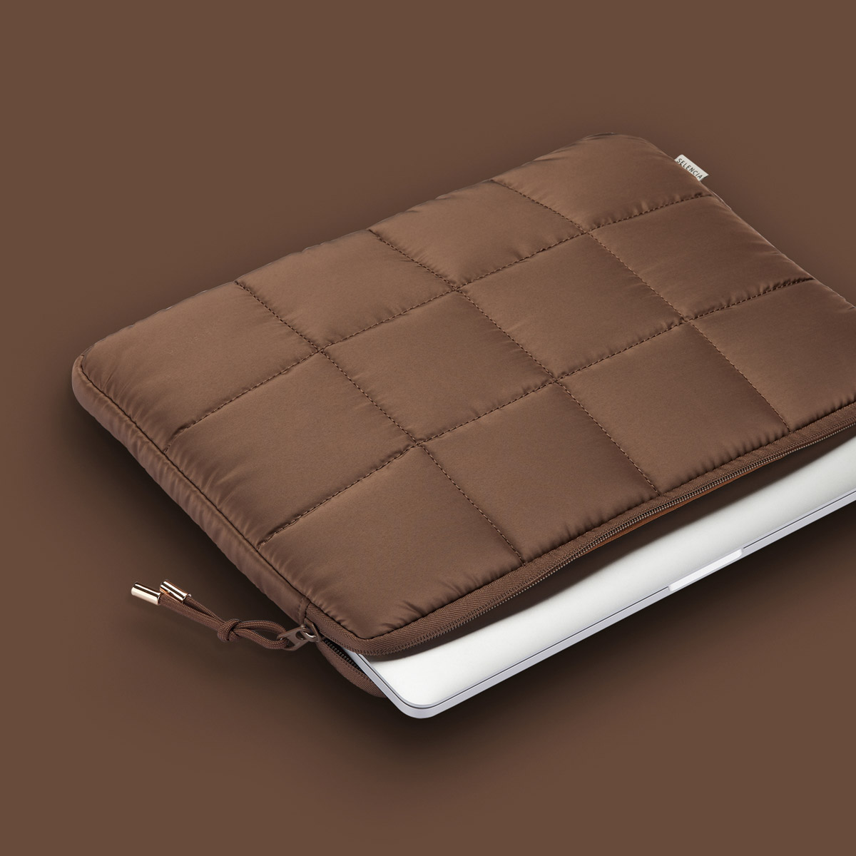 Braune, gesteppte Laptoptasche mit offenem Reißverschluss, der einen Laptop im Inneren zeigt.