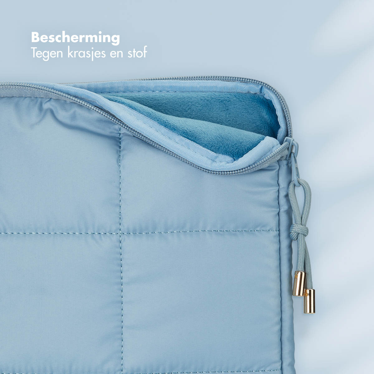 A close-up of a light blue quilted laptop sleeve with a zipper and a blue interior.