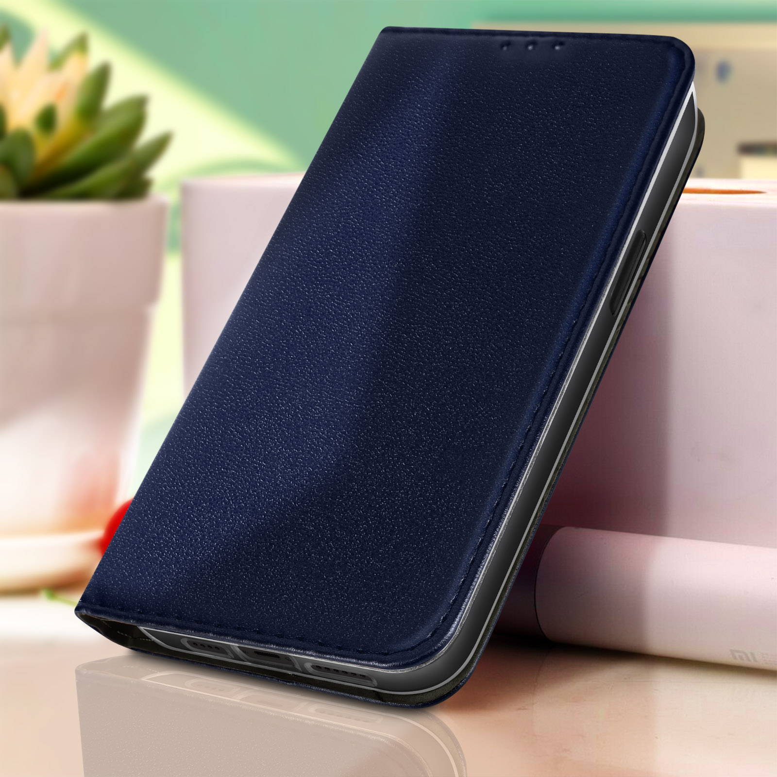 Custodia per telefono blu scuro chiusa con una consistenza liscia simile alla pelle, leggermente angolata, su un tavolo.
