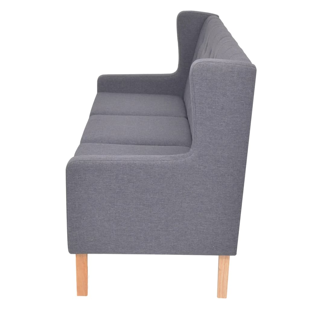 Ein graues Sofa mit hohem Rücken und Holzbeinen, von der Seite betrachtet.