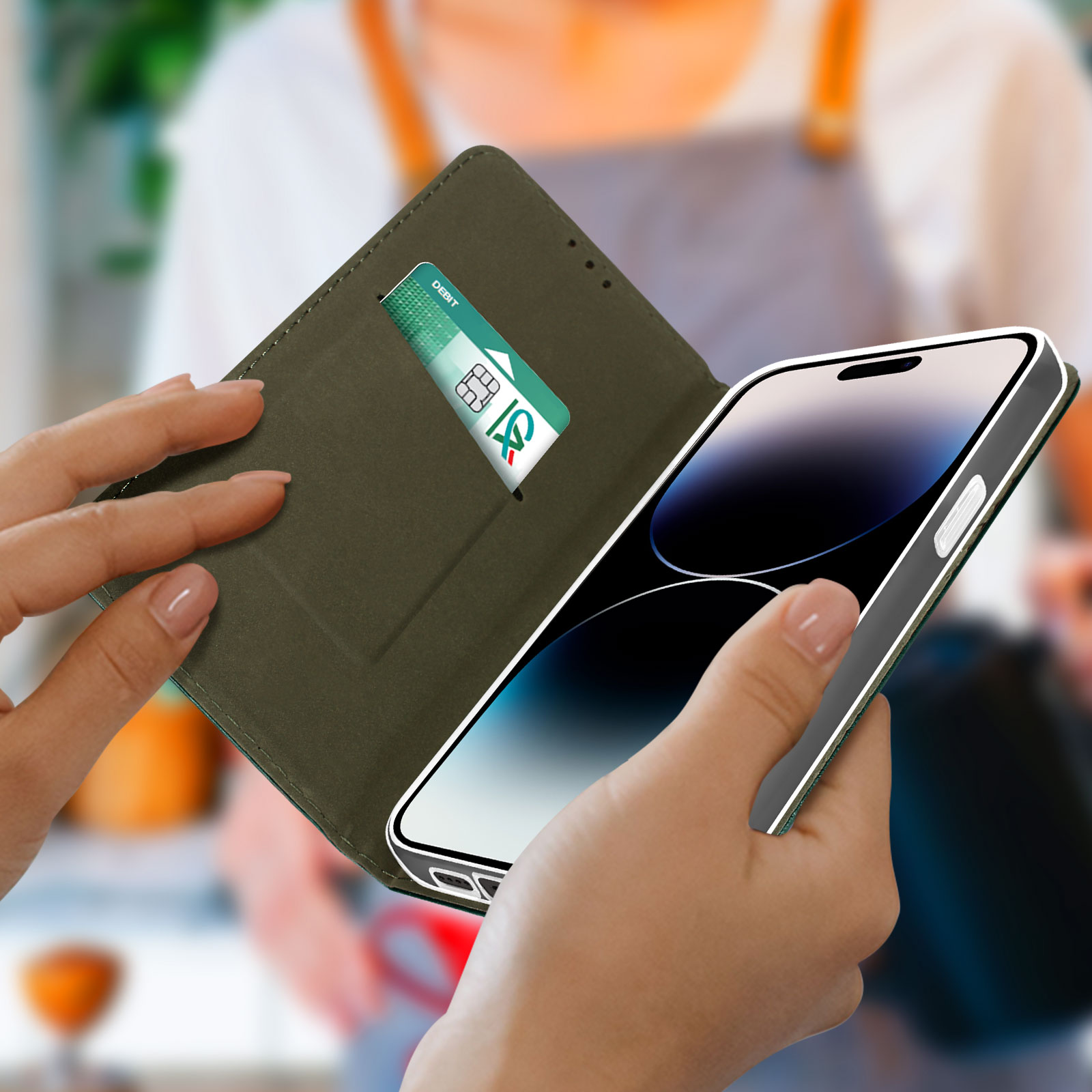 Una persona tiene in mano un telefono in una custodia verde con una carta di credito in tasca.
