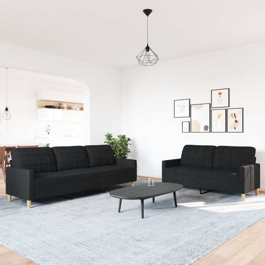Ein Wohnzimmer mit einem schwarzen Sofasatz und einem Couchtisch auf einem Teppich.
