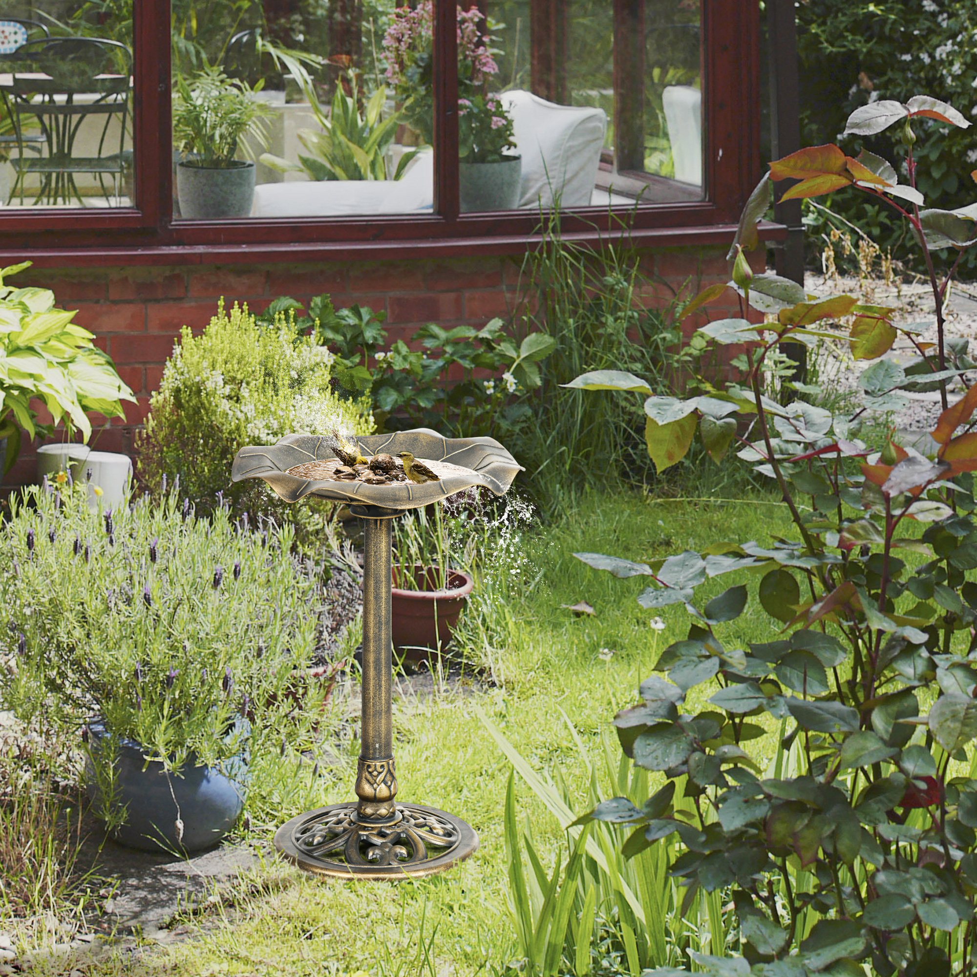 Verzierter Vogelbad im Garten mit Blumen und grünem Gras.