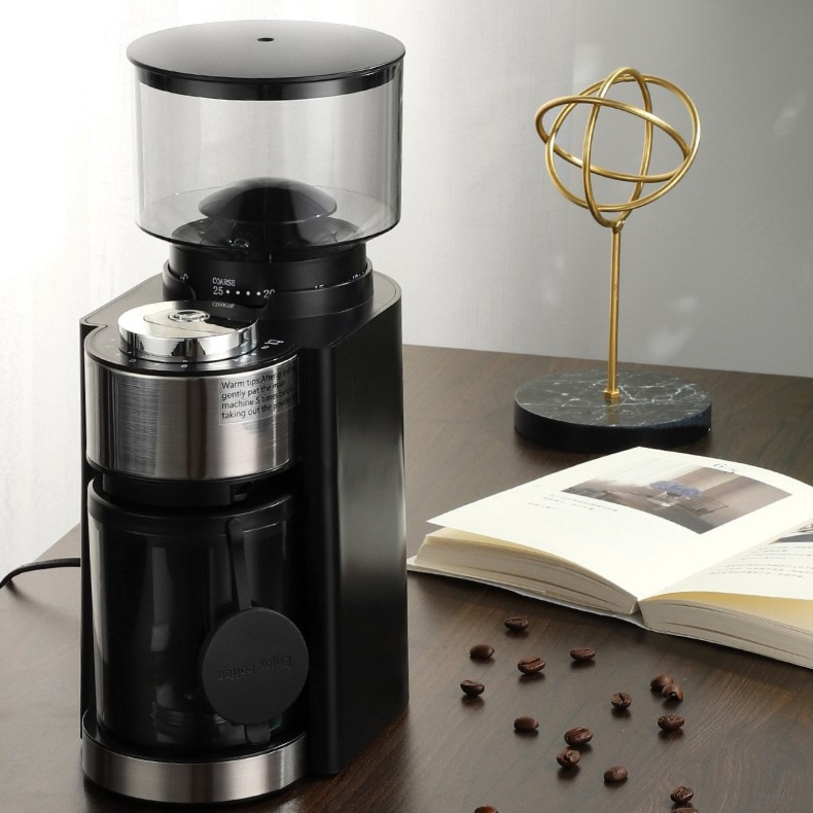 Schwarze Kaffeemühle mit transparentem Behälter und goldener Skulptur.