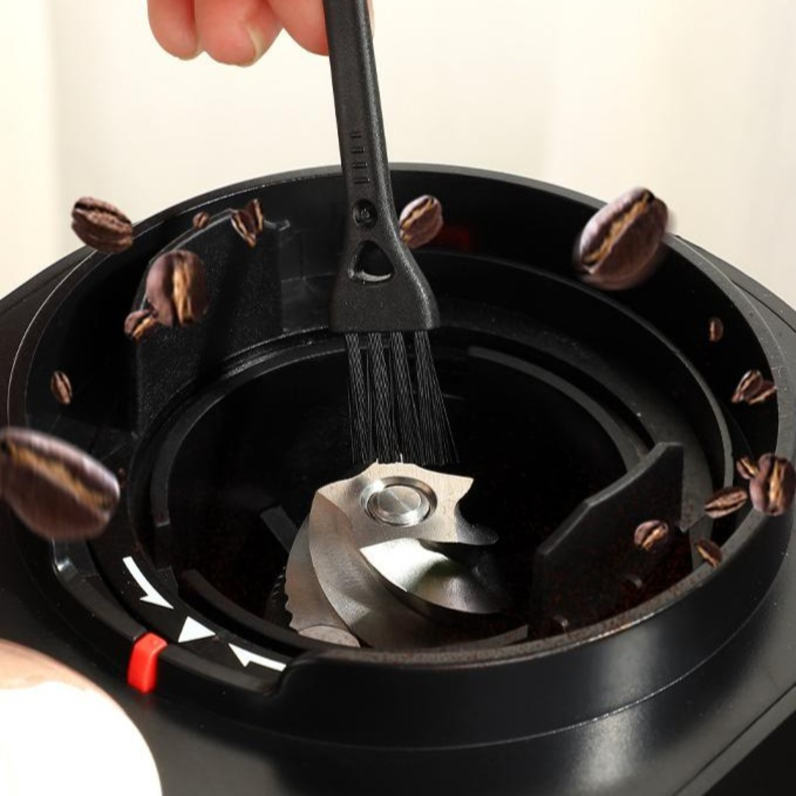 Kaffeebohnen werden aus einer Mühle gebürstet. Eine Bürste wird zum Reinigen der Klingen verwendet.