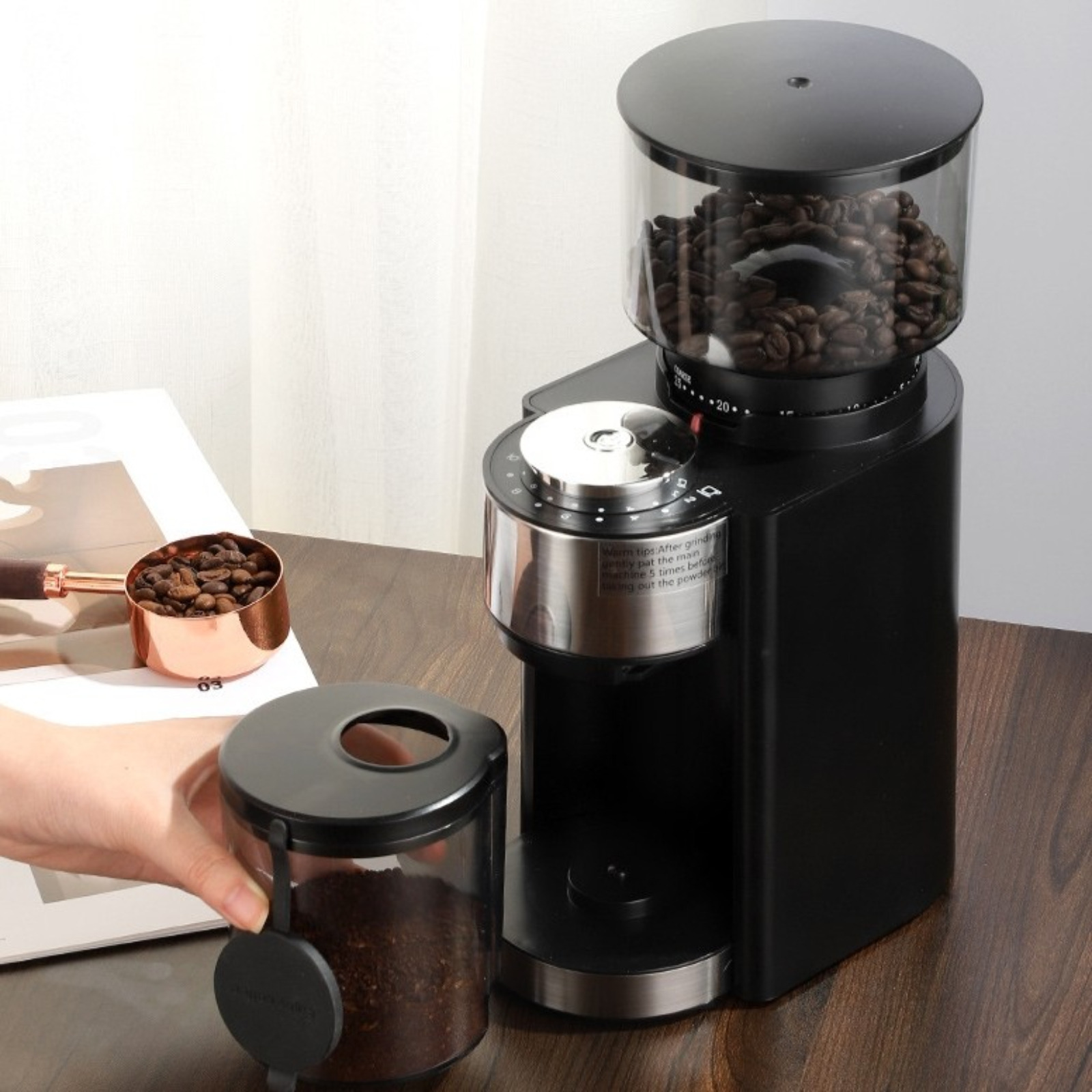 Schwarze Kaffeemühle mit vollem Bohnenbehälter. Ein kleiner Behälter enthält gemahlenen Kaffee.