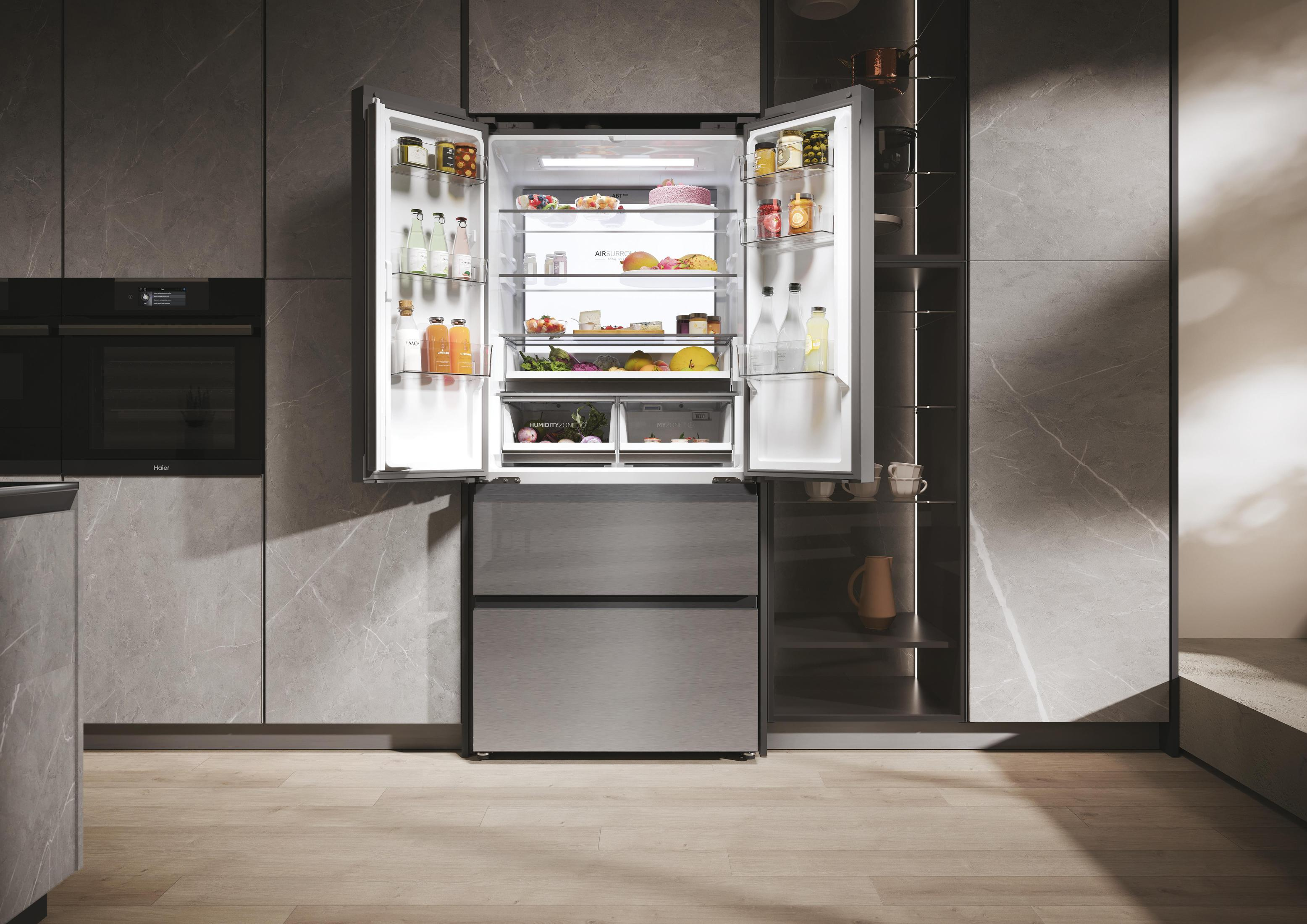 Refrigerador moderno abierto con comida dentro. Cocina con pared de mármol y suelo de madera.
