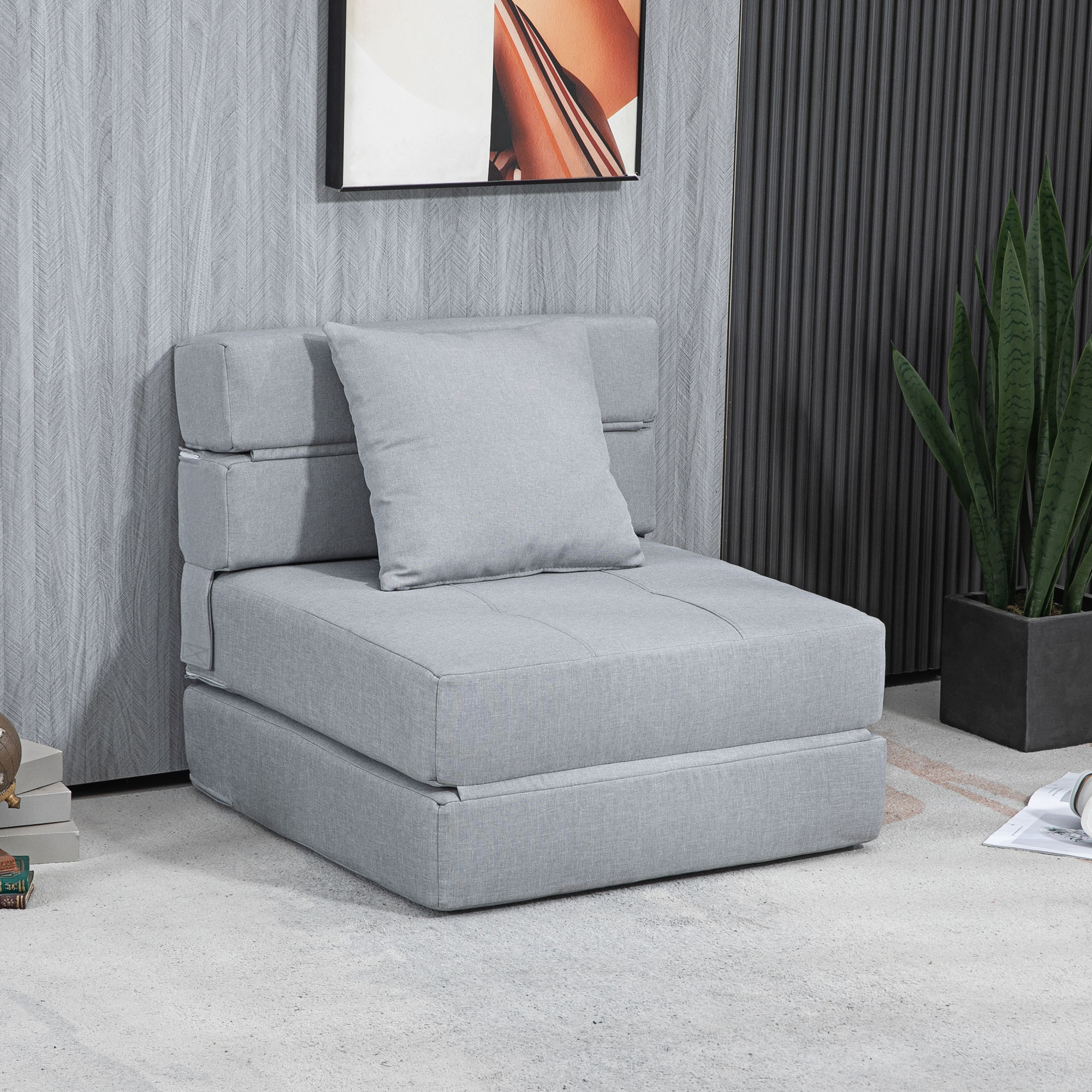 Graues, wandelbares Sofa in einer Raumeinstellung. Es hat ein graues Kissen und eine Pflanze im Hintergrund.