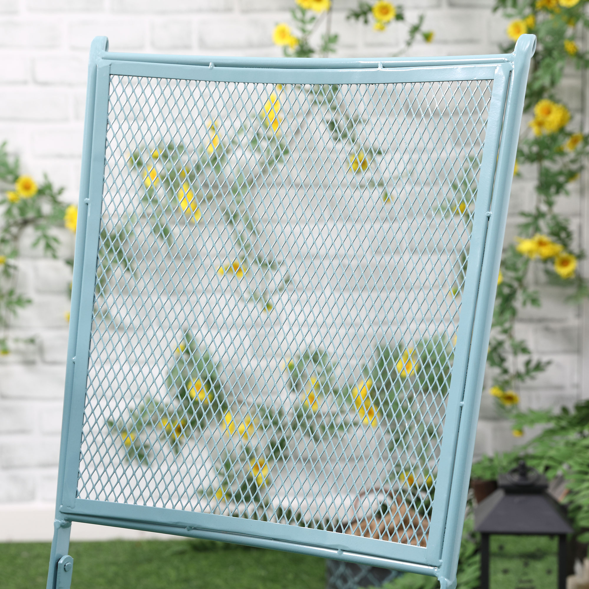 Hellblauer Metallstuhl mit Rautenmuster, mit floralem Hintergrund.