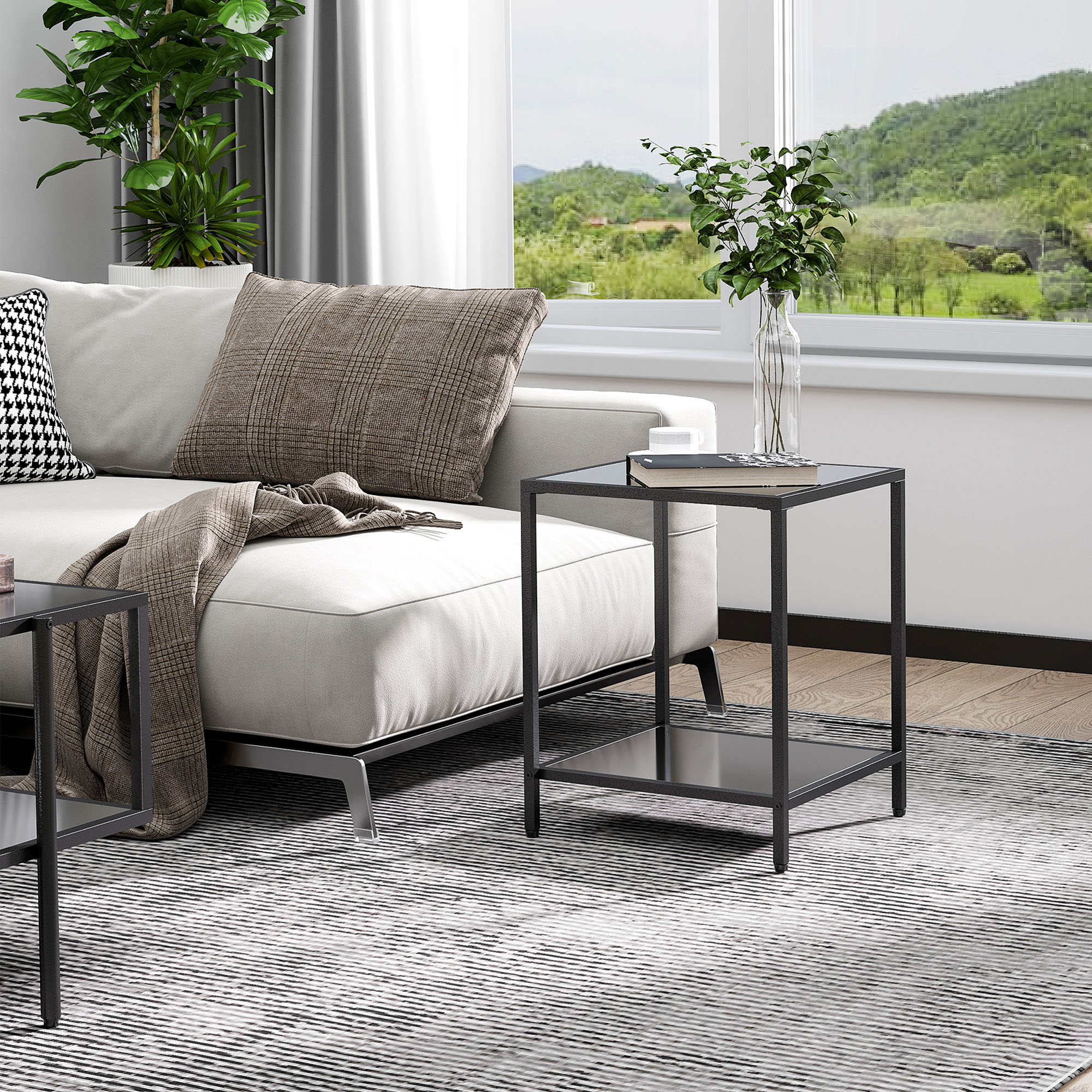Ein Wohnzimmer mit weißem Sofa, Kissen und Beistelltisch. Ein Fenster zeigt einen Blick auf grüne Hügel.