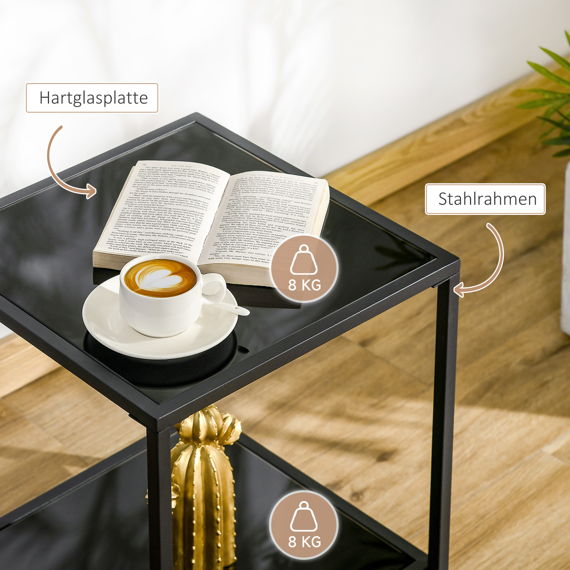 Schwarzer Beistelltisch mit Buch, Kaffee und goldener Kaktus. Hintergrund unscharf.