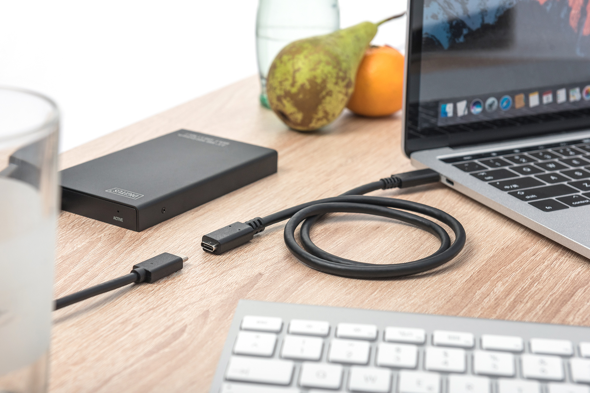 Laptop, der über ein USB-C-Kabel mit einer externen Festplatte verbunden ist. Weitere Artikel vorhanden.