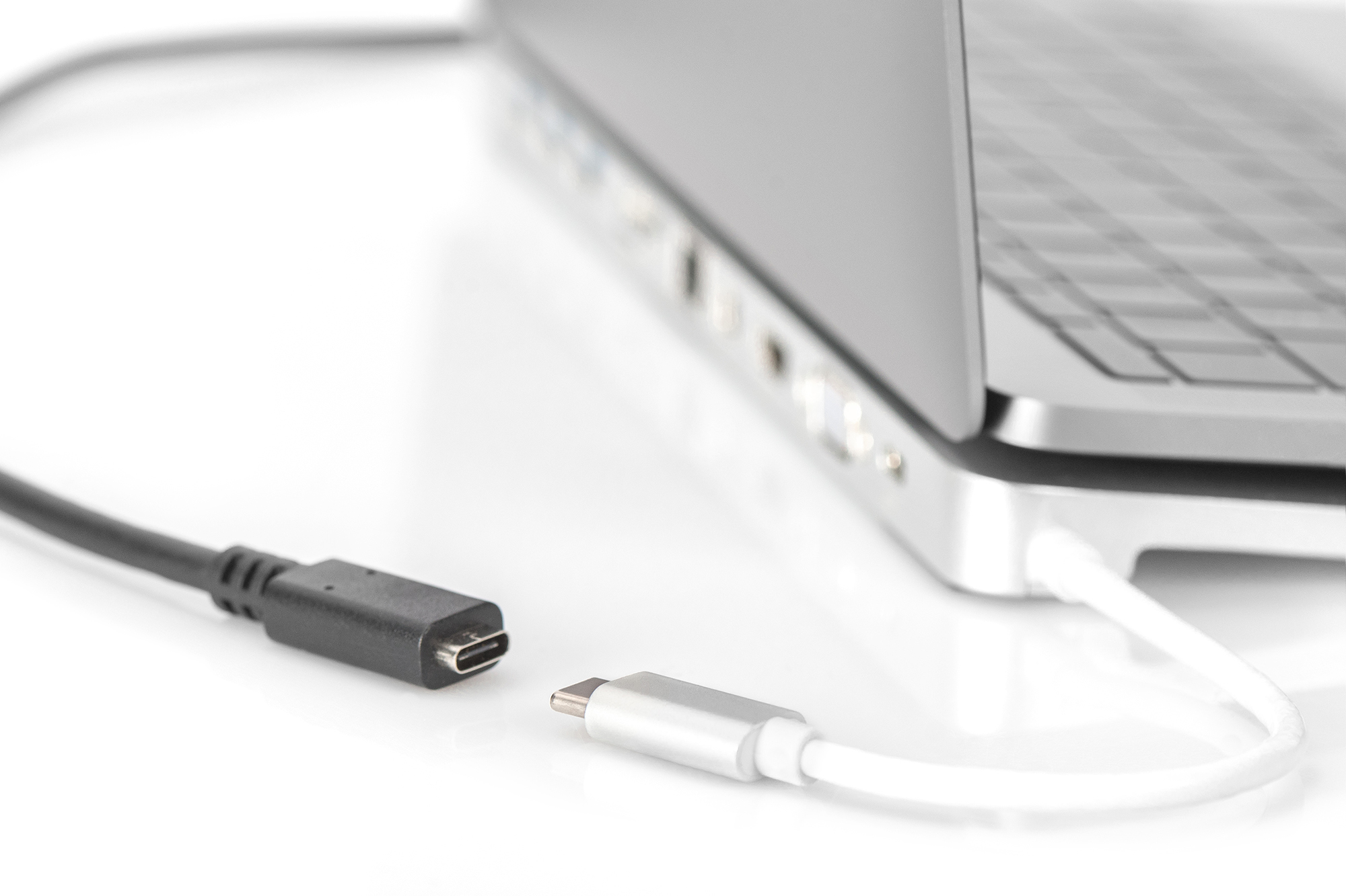 Laptop en twee kabels. Eén heeft een USB-C-connector naar de laptop en een USB-C naar USB-A-kabel.