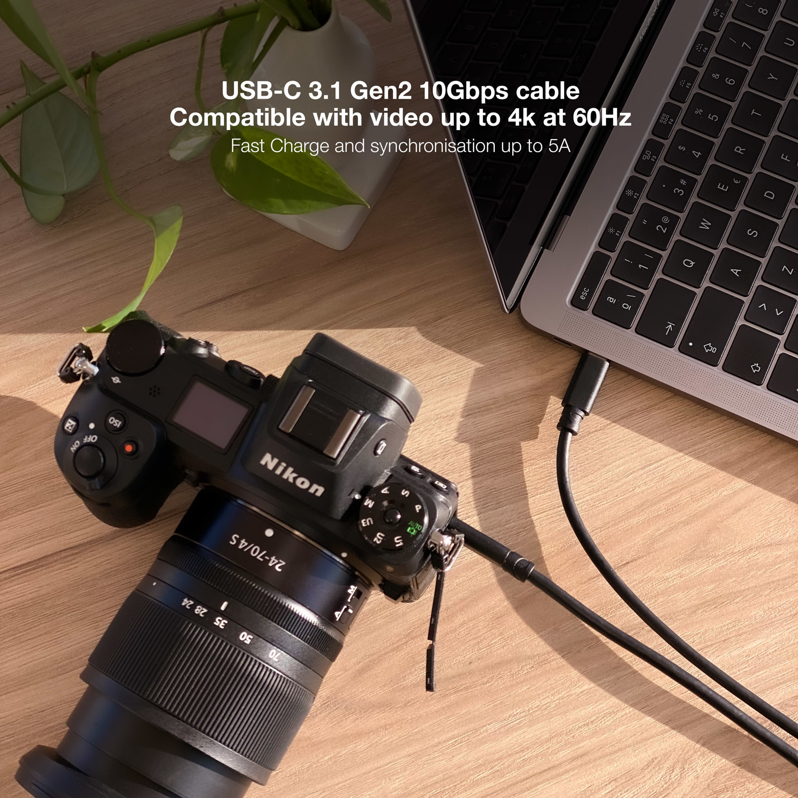 Een camera aangesloten op een laptop met een USB-C-kabel, op een houten oppervlak.