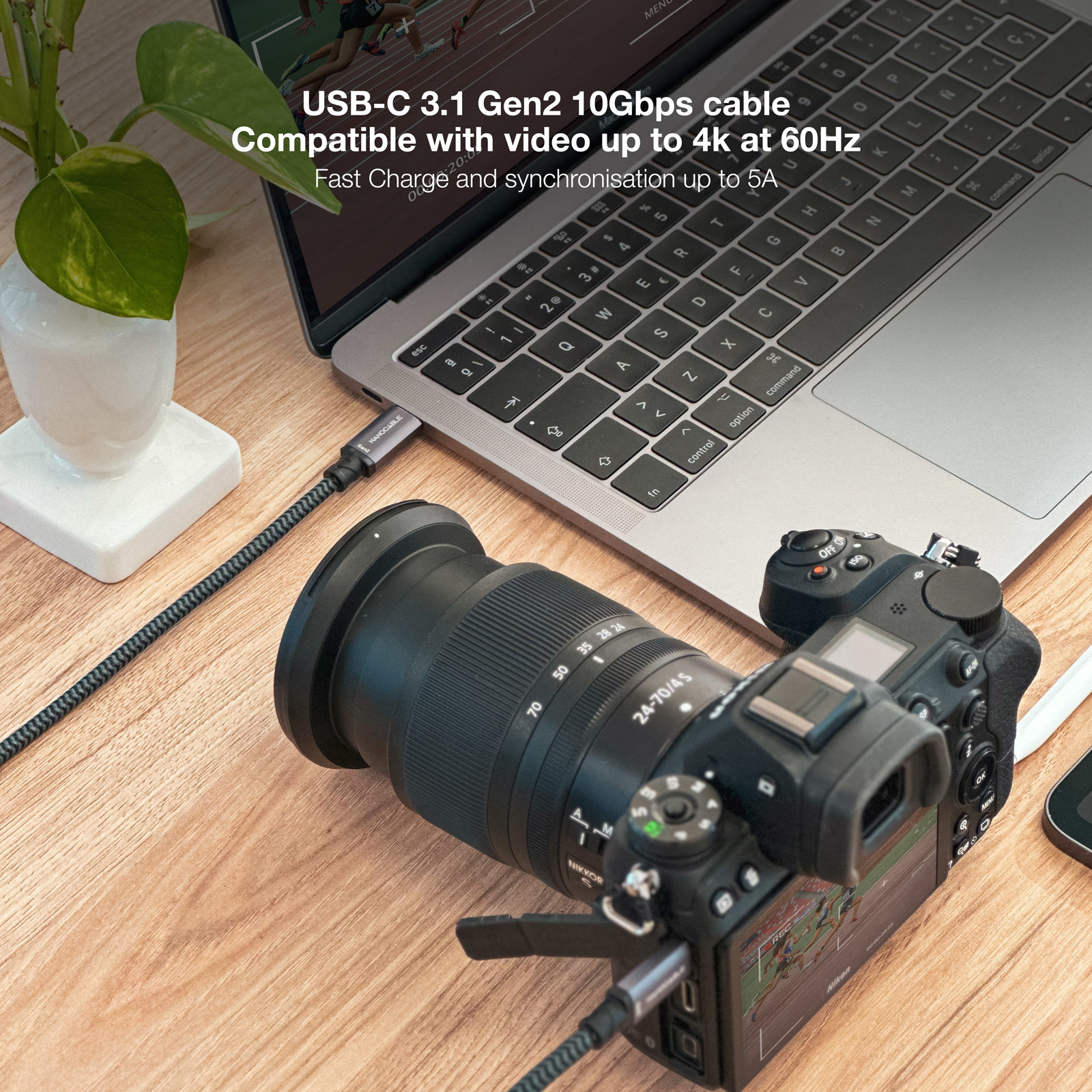 Laptop podłączony do aparatu kablem USB-C na drewnianym biurku.