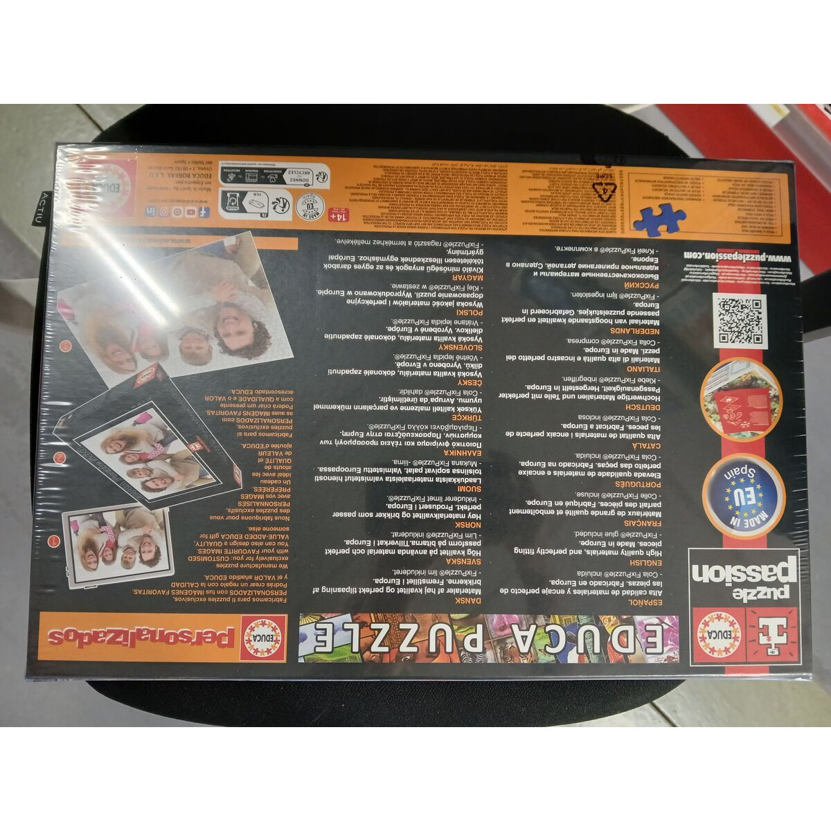 Pudełko z puzzlami ze zdjęciami ludzi i tekstem w różnych językach.