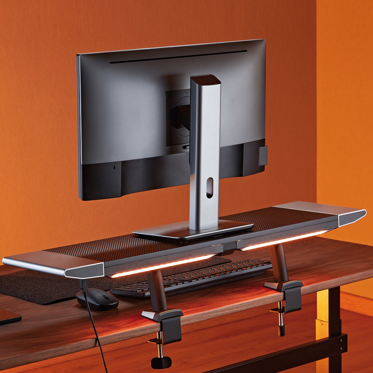 Rückseite eines Monitors auf einem Schreibtisch. Der Hintergrund ist orange.