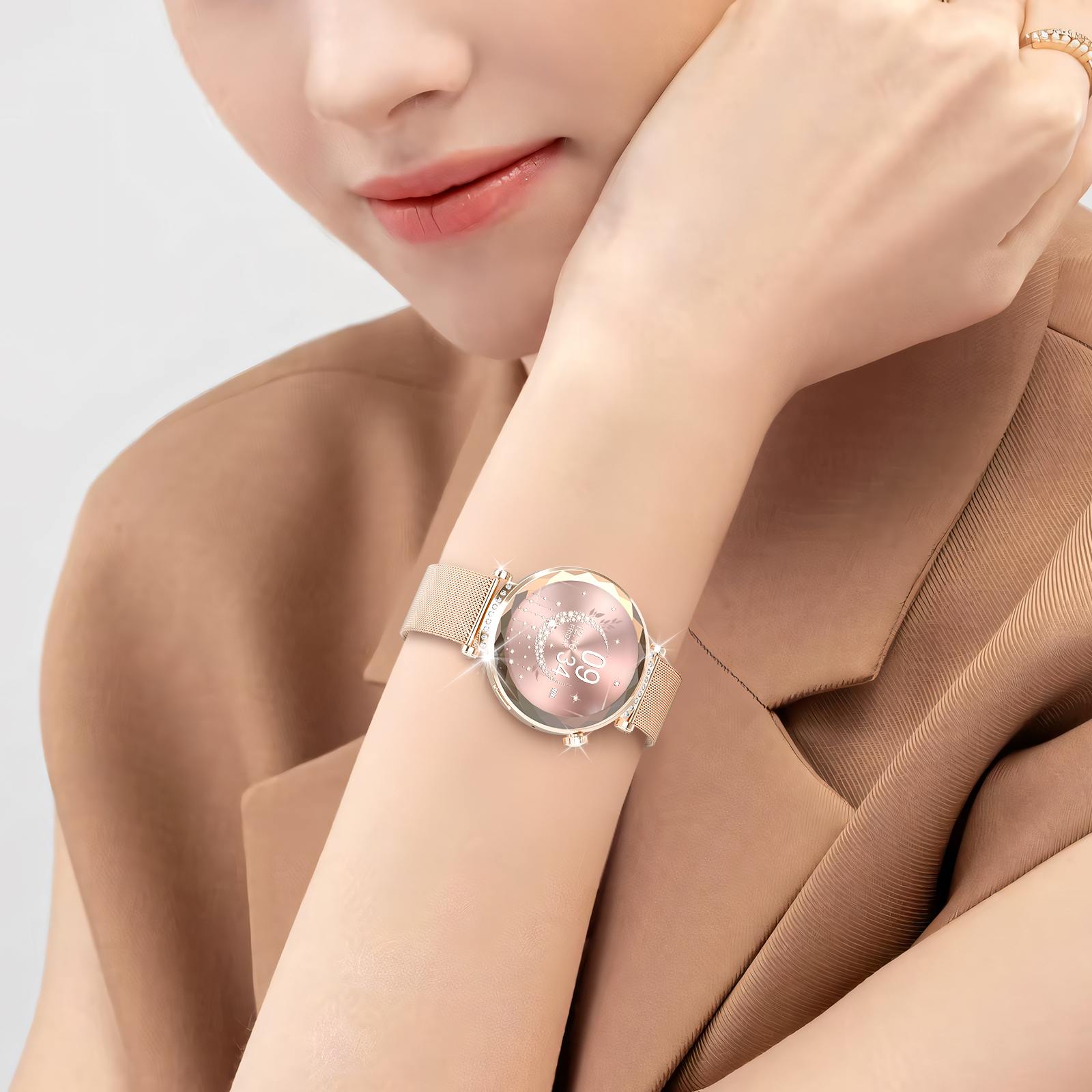 Das Handgelenk einer Frau mit einer Armbanduhr. Die Uhr hat ein rosa Zifferblatt und ein Mesh-Armband.