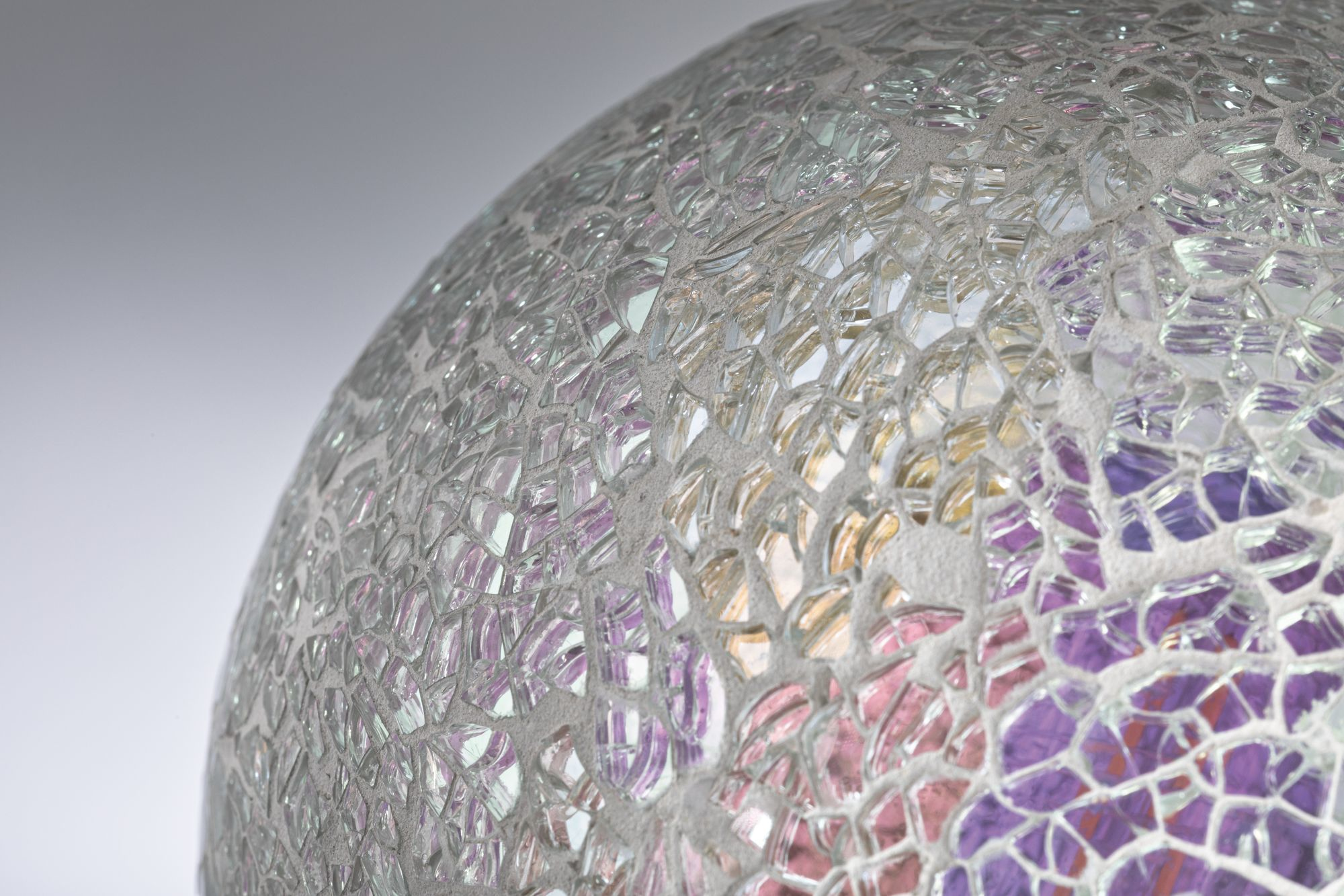 Zbliżenie dekoracyjnej szklanej kuli z popękaną, mozaikową powierzchnią.