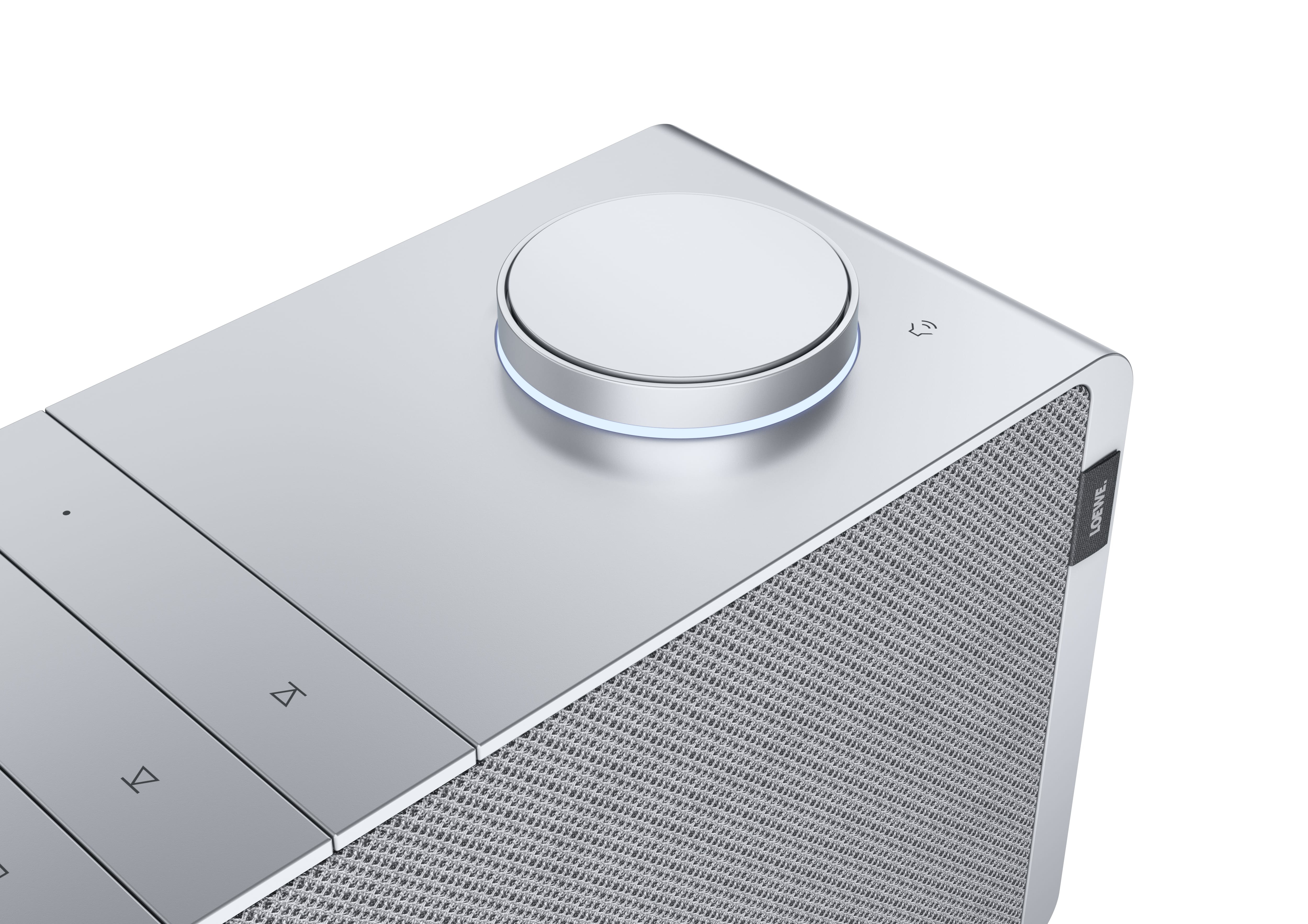 Zbliżenie srebrnego głośnika. Posiada centralne pokrętło sterowania i kratkę głośnika.