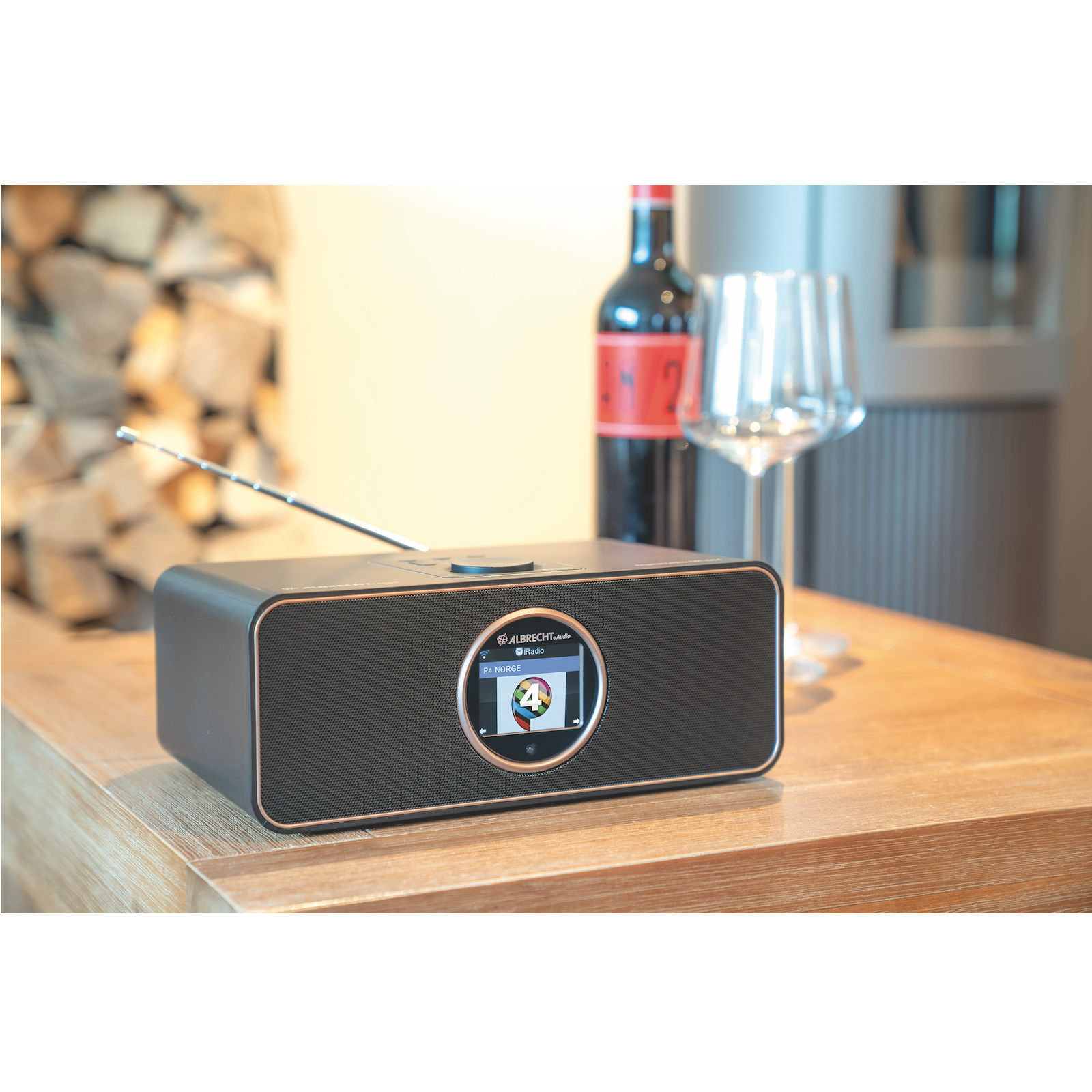 Une radio noire avec écran, du vin et un verre sur une table en bois.