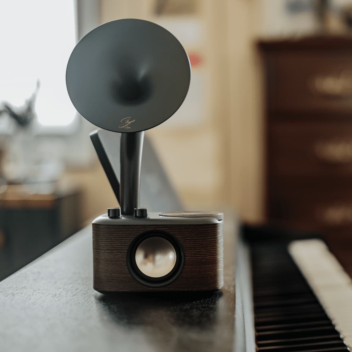 Un altavoz negro con una bocina. El altavoz está en un piano. El fondo está borroso.