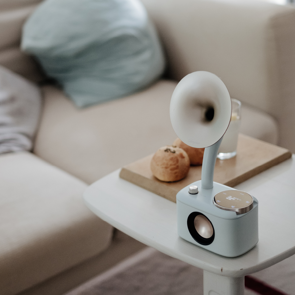 Głośnik retro z jasnoniebieskim korpusem i białym głośnikiem w kształcie rogu. Inne przedmioty na stole.