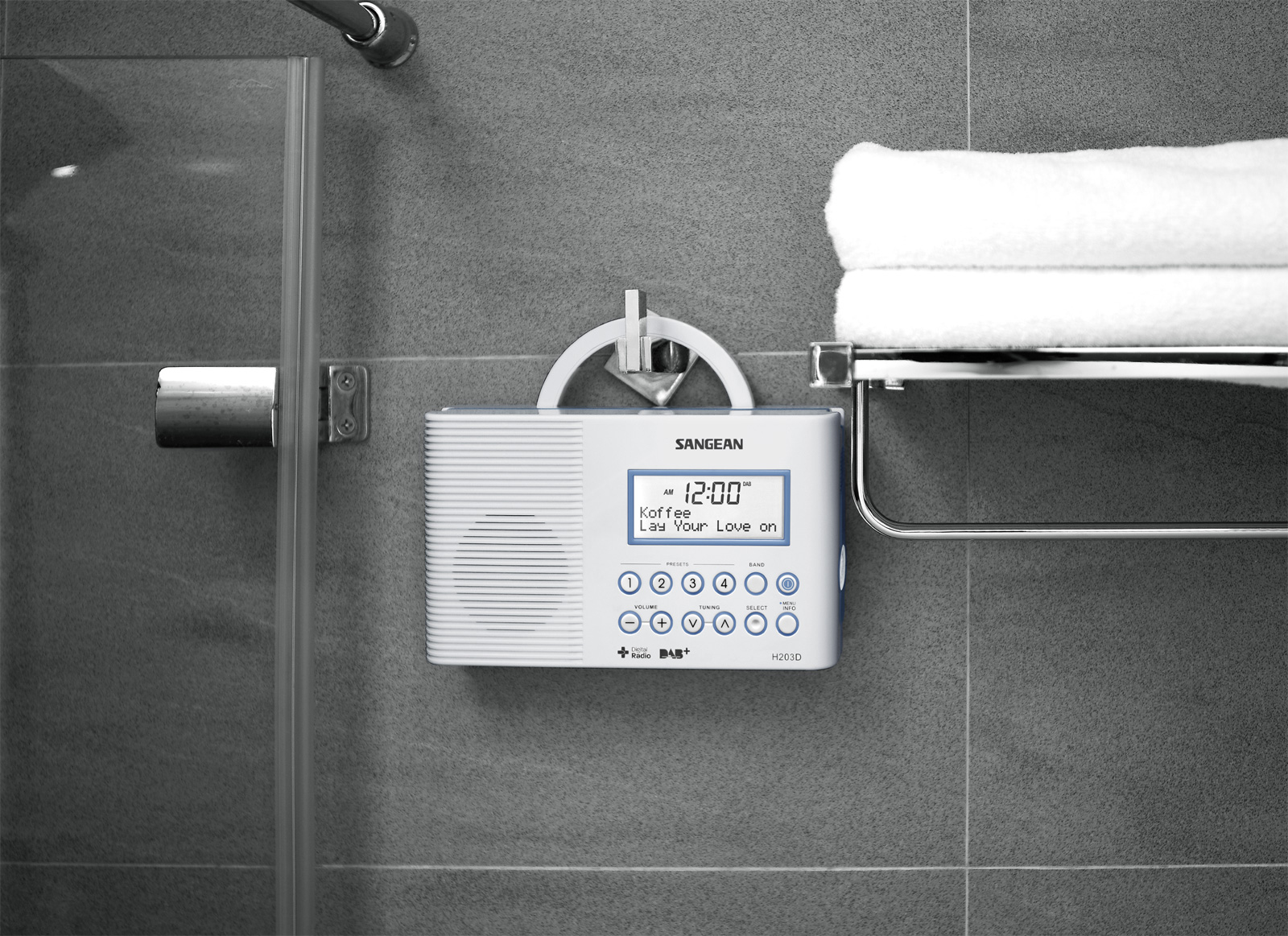 Biało-szare radio z zegarem cyfrowym, zamontowane na szarej kafelkowej ścianie obok wieszaka na ręczniki.