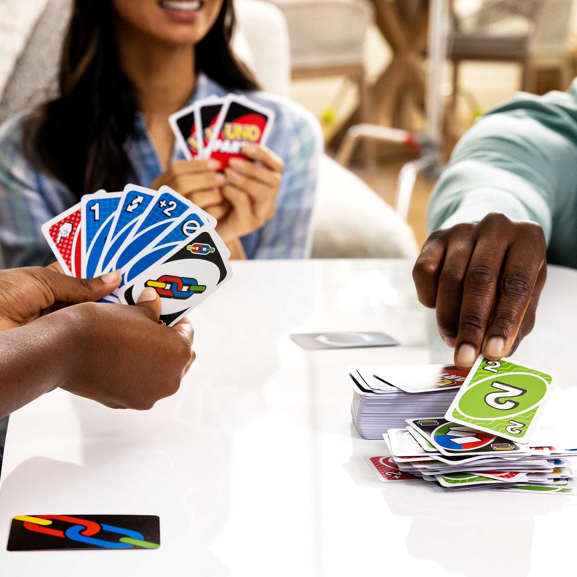 Des personnes jouant à un jeu de cartes, montrant des cartes et des mains. Surface blanche.