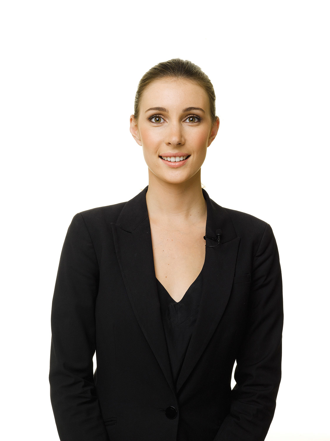 Donna in blazer nero sorride su sfondo bianco.
