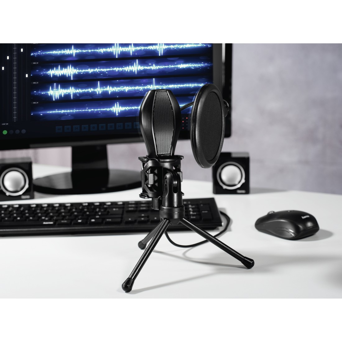 Ein Mikrofon mit Pop-Filter und zwei Lautsprechern auf einem Schreibtisch.