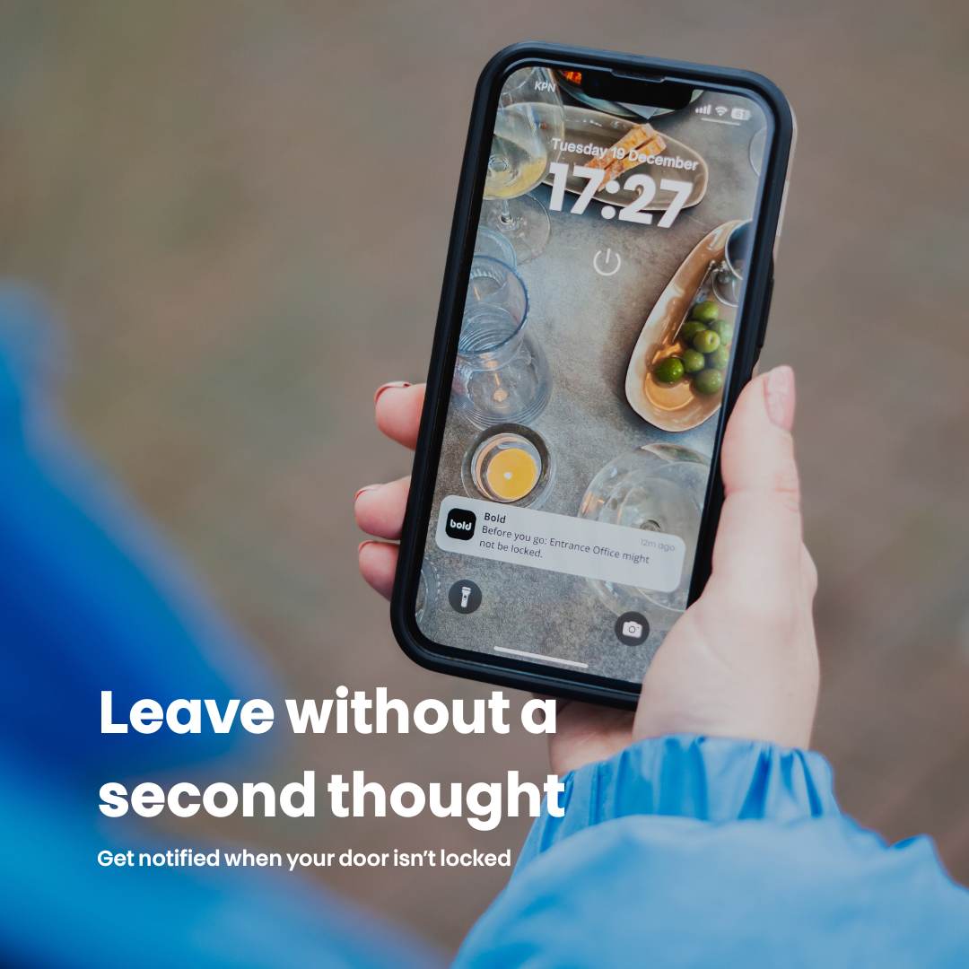 A person is holding a phone showing a lock screen with the time and a notification.