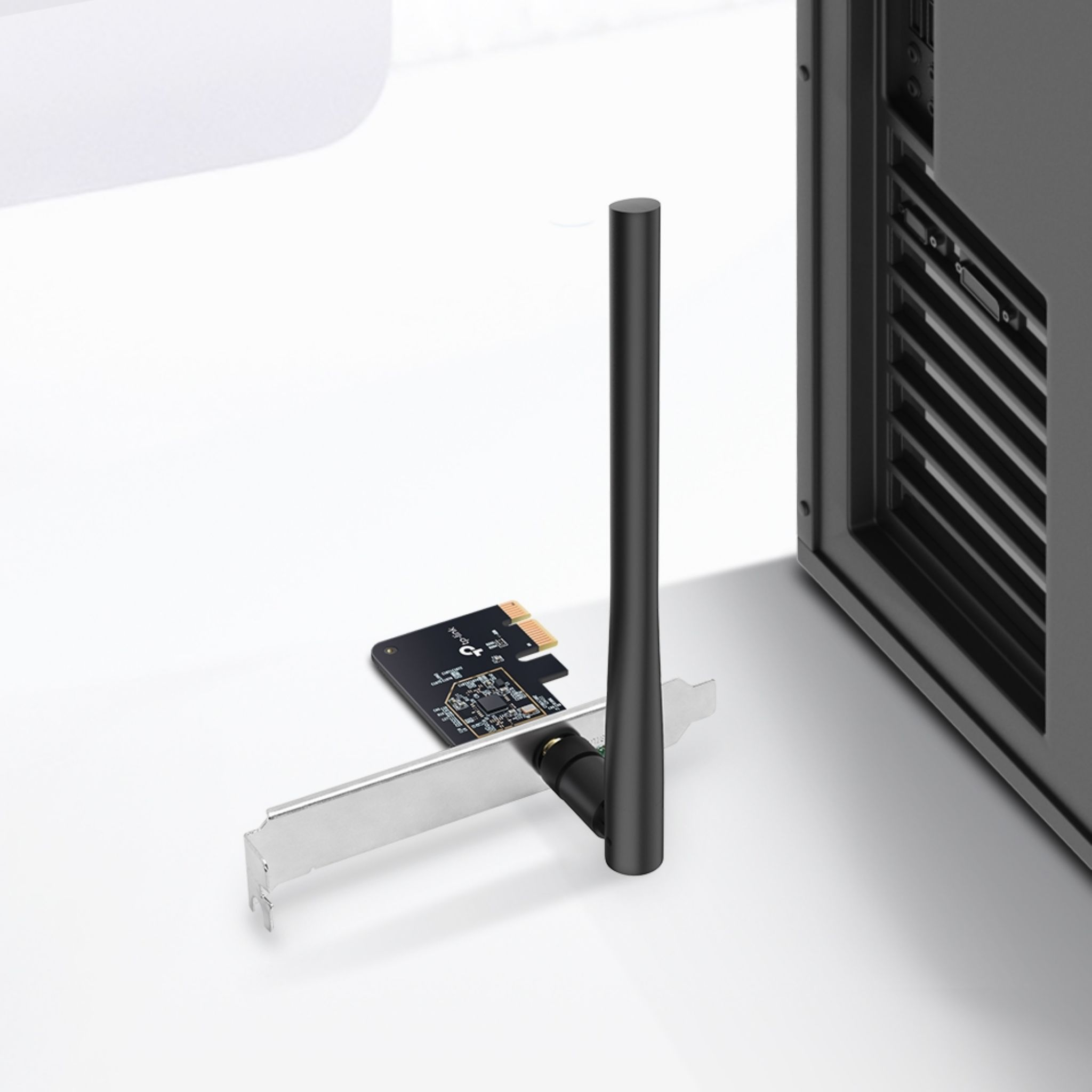 A black WiFi adapter with an antenna next to a computer case.