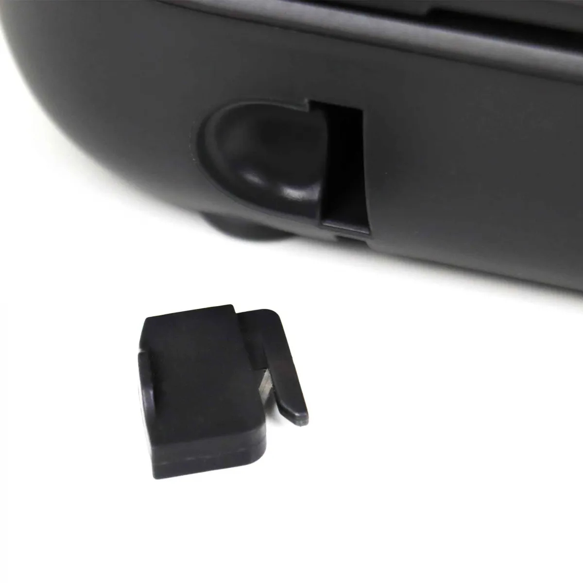 Zbliżenie czarnego plastikowego elementu odłączonego od czarnego urządzenia. Białe tło.