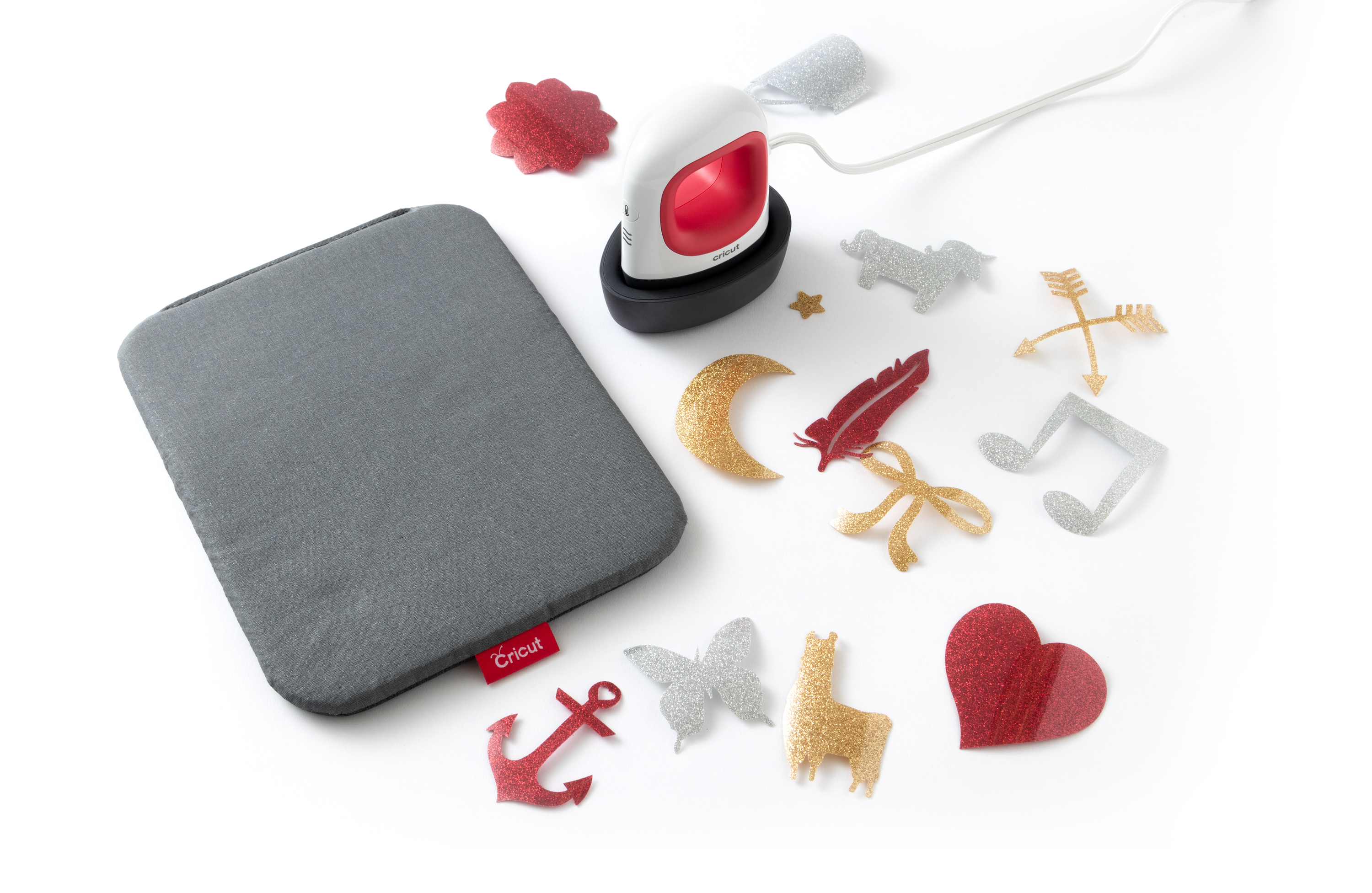 Weiß-rote Cricut-Heißpresse mit verschiedenen Glitzerformen und einer grauen Matte.