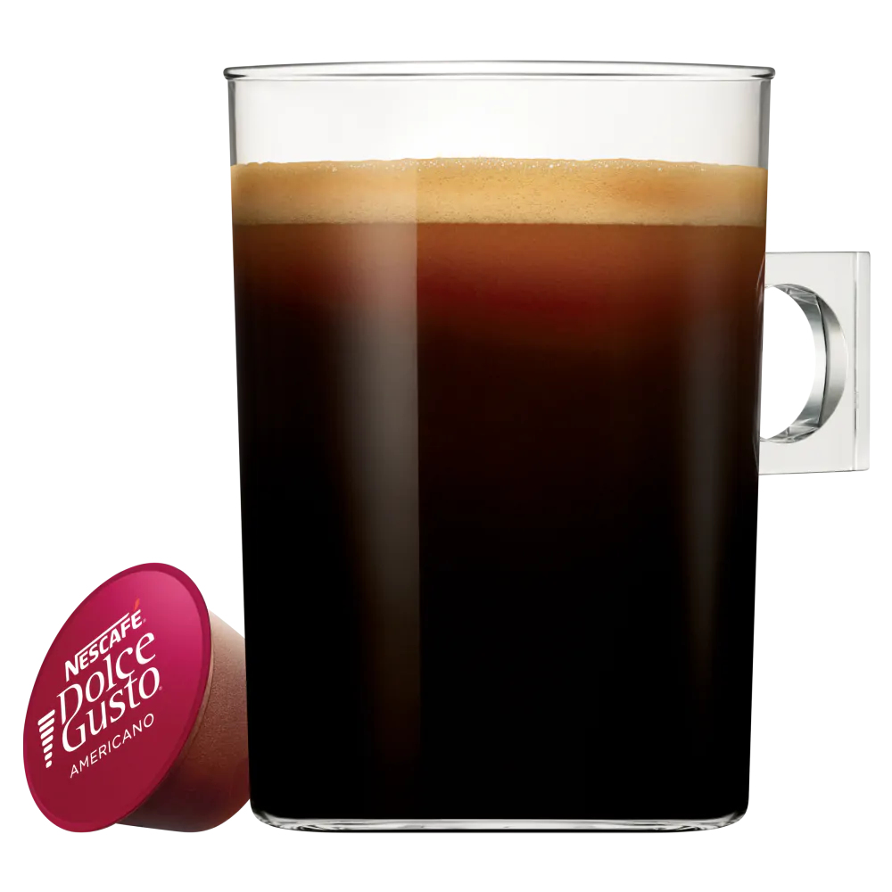 Una tazza di vetro piena di caffè scuro con schiuma. Una capsula di caffè rossa è accanto.